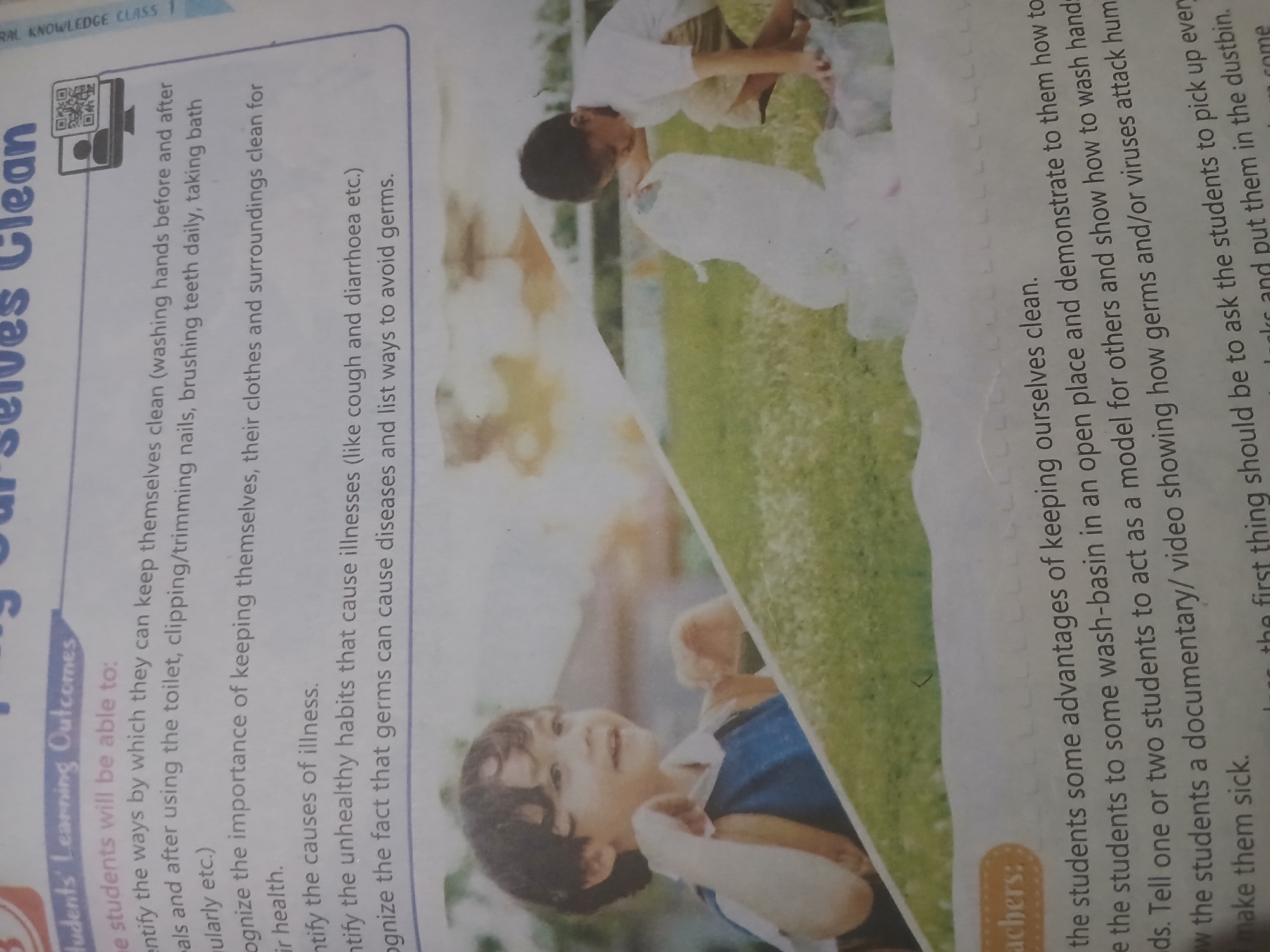 The image is a page from a textbook or educational material, possibly for children, with the title "Keeping Ourselves Clean" visible. The top section contains bullet points outlining learning outcomes for students, such as identifying ways to stay clean and understanding the importance of hygiene. Below this text are two photographs. The left photograph features a young boy with dark, curly hair smiling and looking towards the right, with his hands raised slightly. The right photograph shows another young boy, also with dark hair, wearing a light-colored t-shirt and shorts, crouching down and appearing to be picking up or interacting with white plastic bags on a grassy outdoor surface. The background of the photographs is blurred, but suggests an outdoor setting with greenery. The bottom of the page contains text under the heading "Teachers:", with instructions for educators. There is no information within the image that indicates a location in Peshawar City Tehsil, Pakistan.