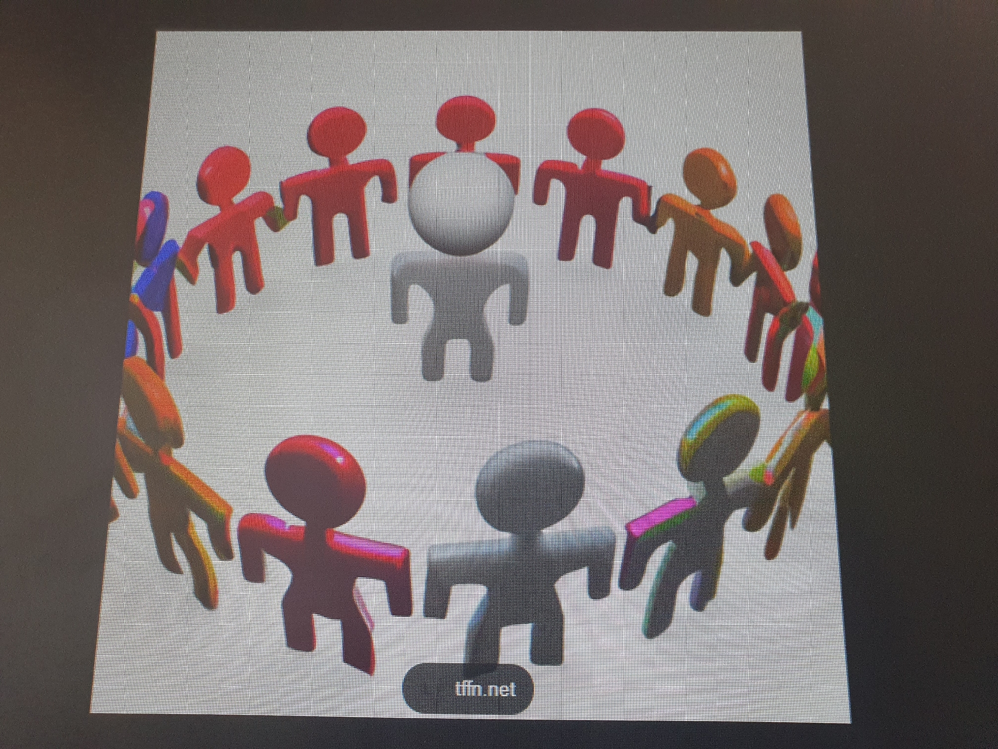 The image displays a 3D rendering of a group of stylized figures, resembling simplified human shapes with round heads and stick-like limbs. They are arranged in a circular formation, holding hands. The figures are a variety of colors, including red, orange, blue, and purple. Two figures in the center are gray and white, with the white figure appearing larger and more prominent. The background is a plain, light gray. In the lower center of the image, there is a dark gray rectangular button with the text "tffin.net" in white. The image is not located in the city of Tashkent, Uzbekistan.