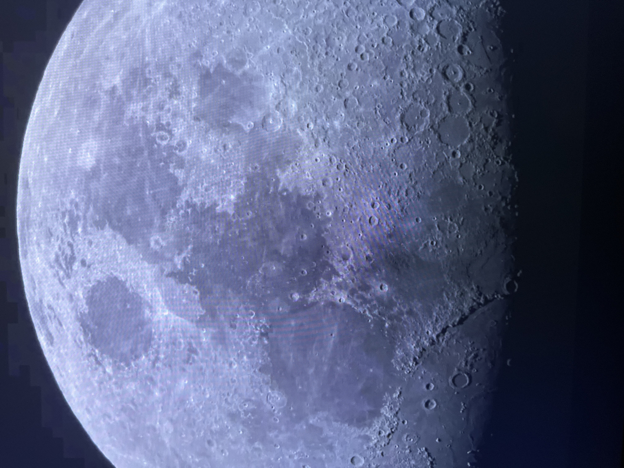 The image shows a close-up view of the Moon. The surface of the Moon is visible, with numerous craters of various sizes and some larger, darker areas that appear to be maria. The lighting suggests that a significant portion of the Moon is illuminated, creating shadows that highlight the topography. There are no people, objects, actions, interactions, or environmental elements identifiable that would suggest a location within the city of Edmonton, Canada, or any specific terrestrial setting.