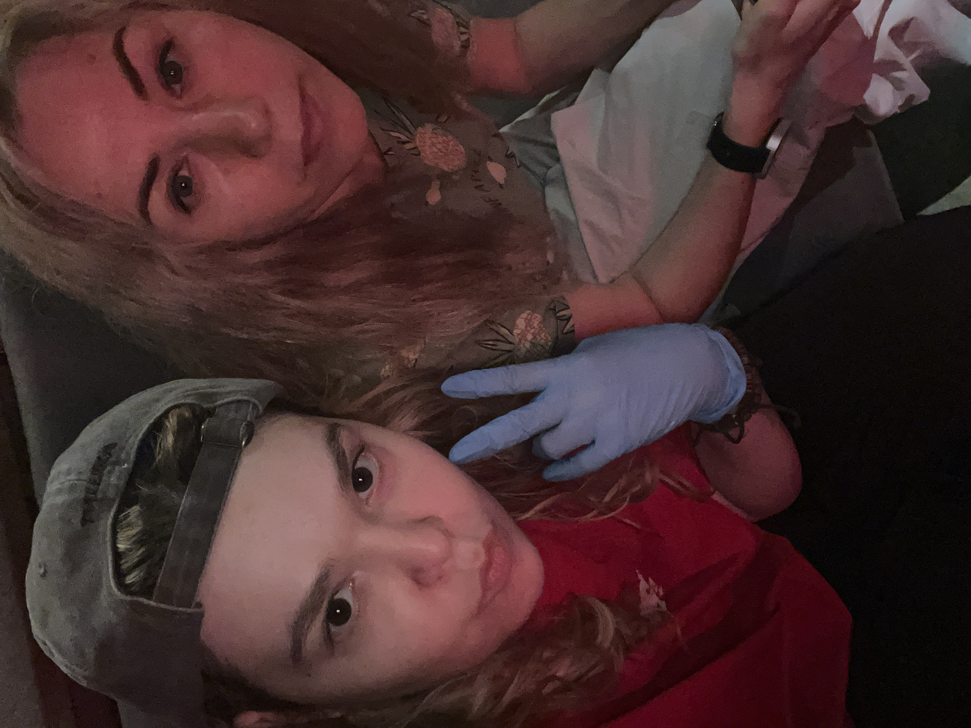 Two individuals are visible in the image. One person is wearing a baseball cap and a red shirt and is making a "peace" sign with a blue glove. The other person is wearing a patterned shirt and has a watch on their wrist. No information is present to determine that this image was taken in Moscow, Russia.