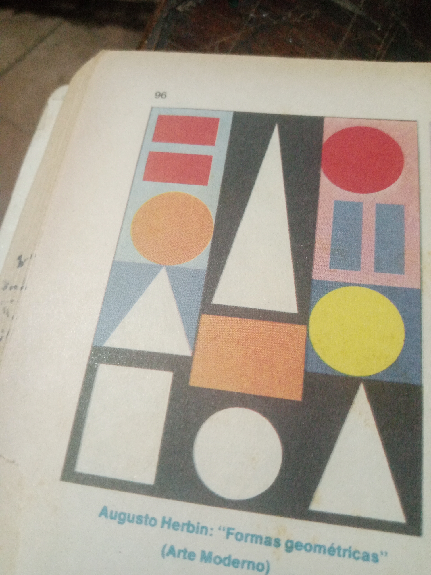 The image displays a page from a book or publication, featuring a colorful geometric abstract artwork attributed to "Augusto Herbin: 'Formas geométricas' (Arte Moderno)". The artwork is composed of various geometric shapes including rectangles, circles, and triangles in red, orange, yellow, white, and blue hues, set against a dark background. A page number "96" is visible in the upper left corner. The text beneath the artwork provides the artist's name and the title of the work. The publication appears to be part of a larger book or document, suggested by the binding and page edges visible in the upper left portion of the image. There is no information within the image to indicate its location in Santa Ana, Venezuela.