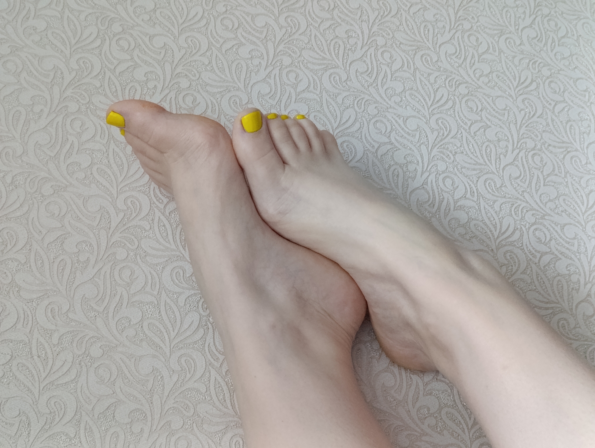 Two feet with yellow nail polish on a patterned surface. No information available to ascertain the location in the city of Unknown, Unknown.