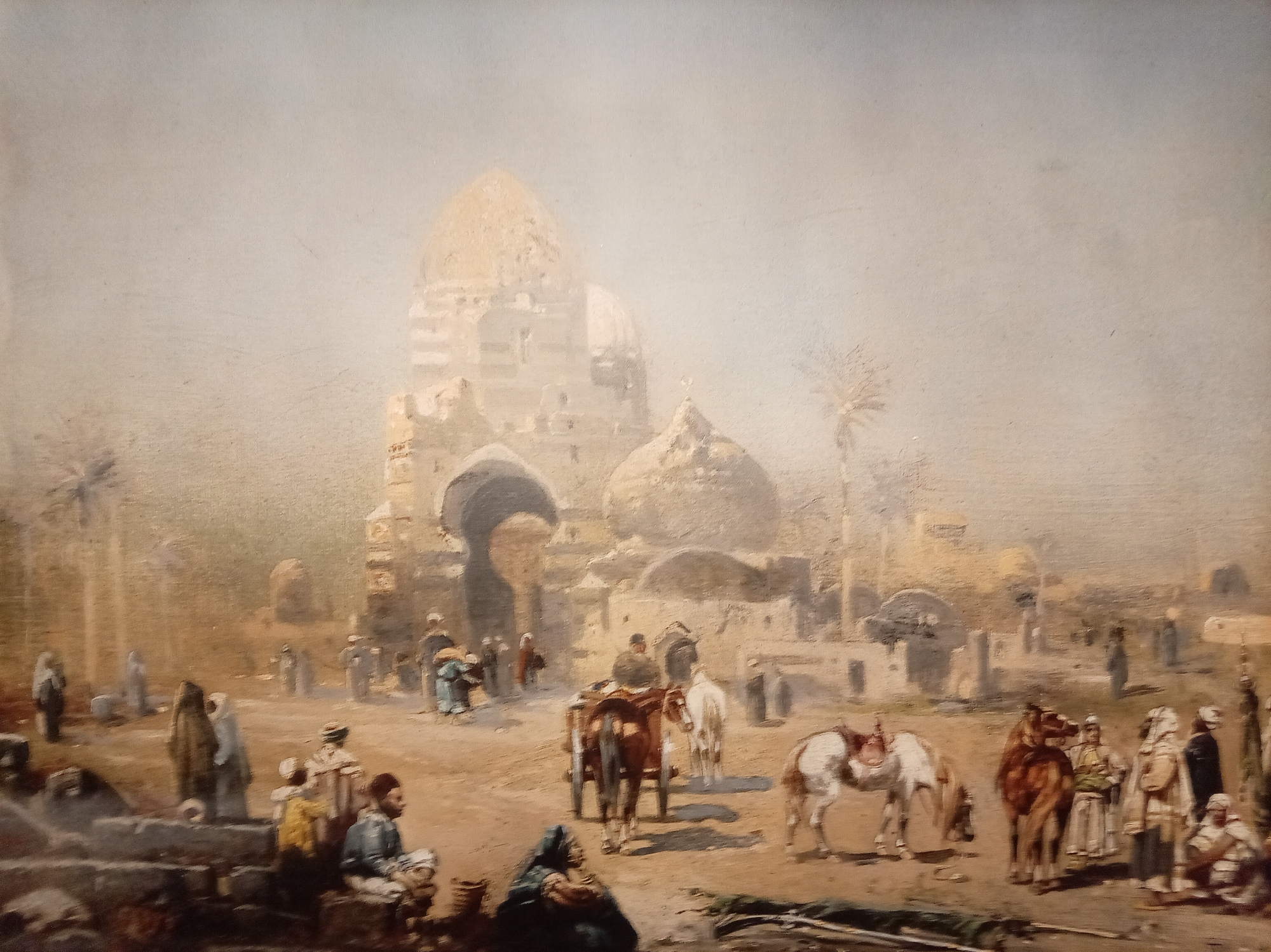 This painting depicts an outdoor scene in what appears to be an ancient city, possibly in the Middle East. In the background, there are large domed structures and other buildings made of stone, suggesting historical or religious significance. Several palm trees are scattered throughout the landscape, indicating a warm climate.
The foreground and mid-ground are populated with numerous figures. People are shown in traditional attire, with some wearing robes and head coverings. There are also several horses and a cart with horses pulling it, suggesting transportation and commerce. Some figures appear to be interacting, with groups gathered in conversation or engaged in activities. The ground is dusty and uneven, typical of an arid environment.
The overall atmosphere is hazy and muted, with a soft, diffused light. The color palette is dominated by earthy tones of brown, beige, and yellow, with some touches of blue and red in the clothing of the figures. The style of painting is realistic, with a focus on capturing the details of the architecture, people, and animals.
There is no indication within the image or accompanying crops that this scene is located in the city of Yessentuki, Russia.