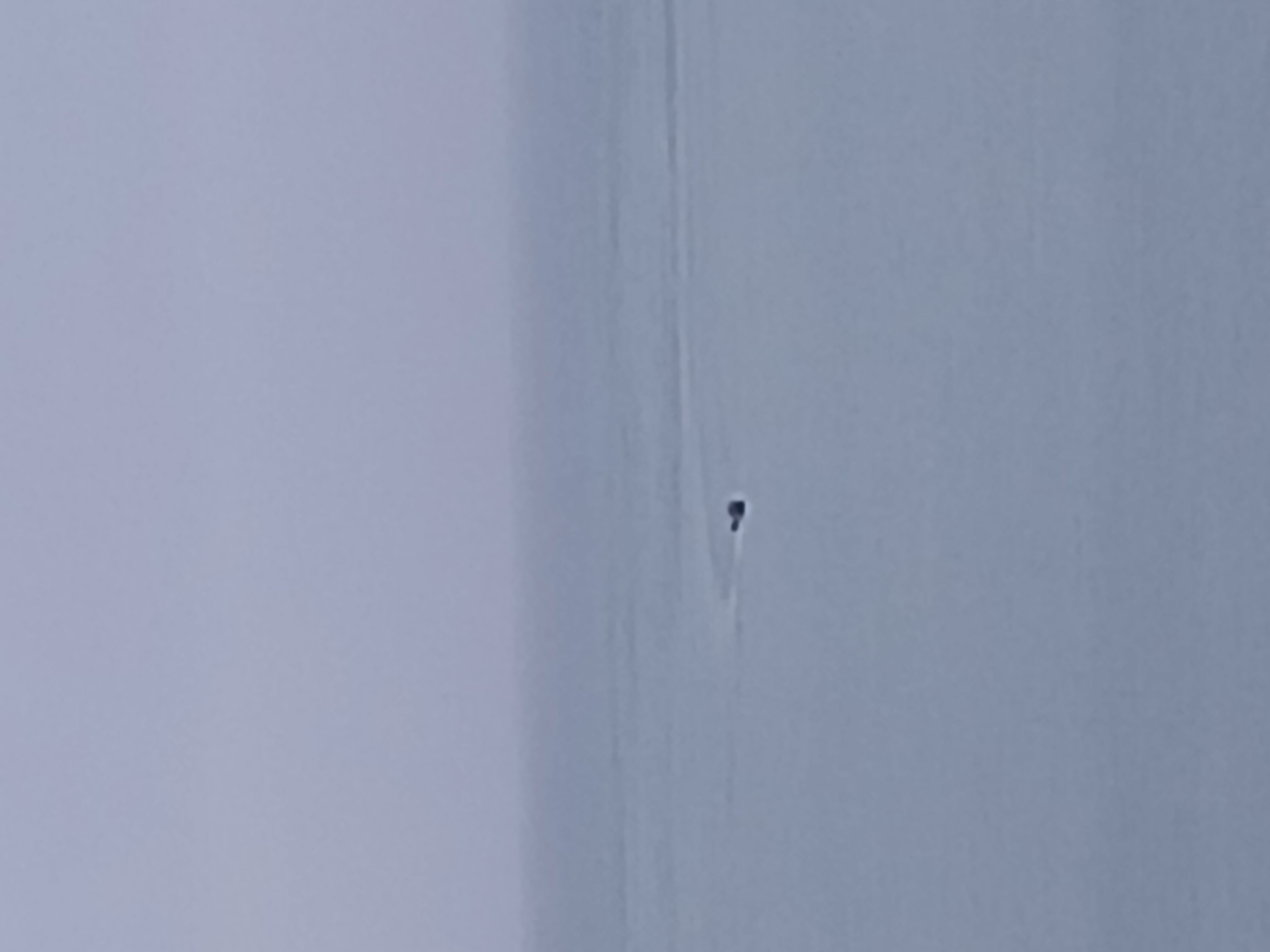 The image shows a detail of an off-white wall or surface, possibly an interior wall or a similar structure, with a small dark imperfection or hole visible. There's no additional context to identify its precise location within Juan Griego, Venezuela.