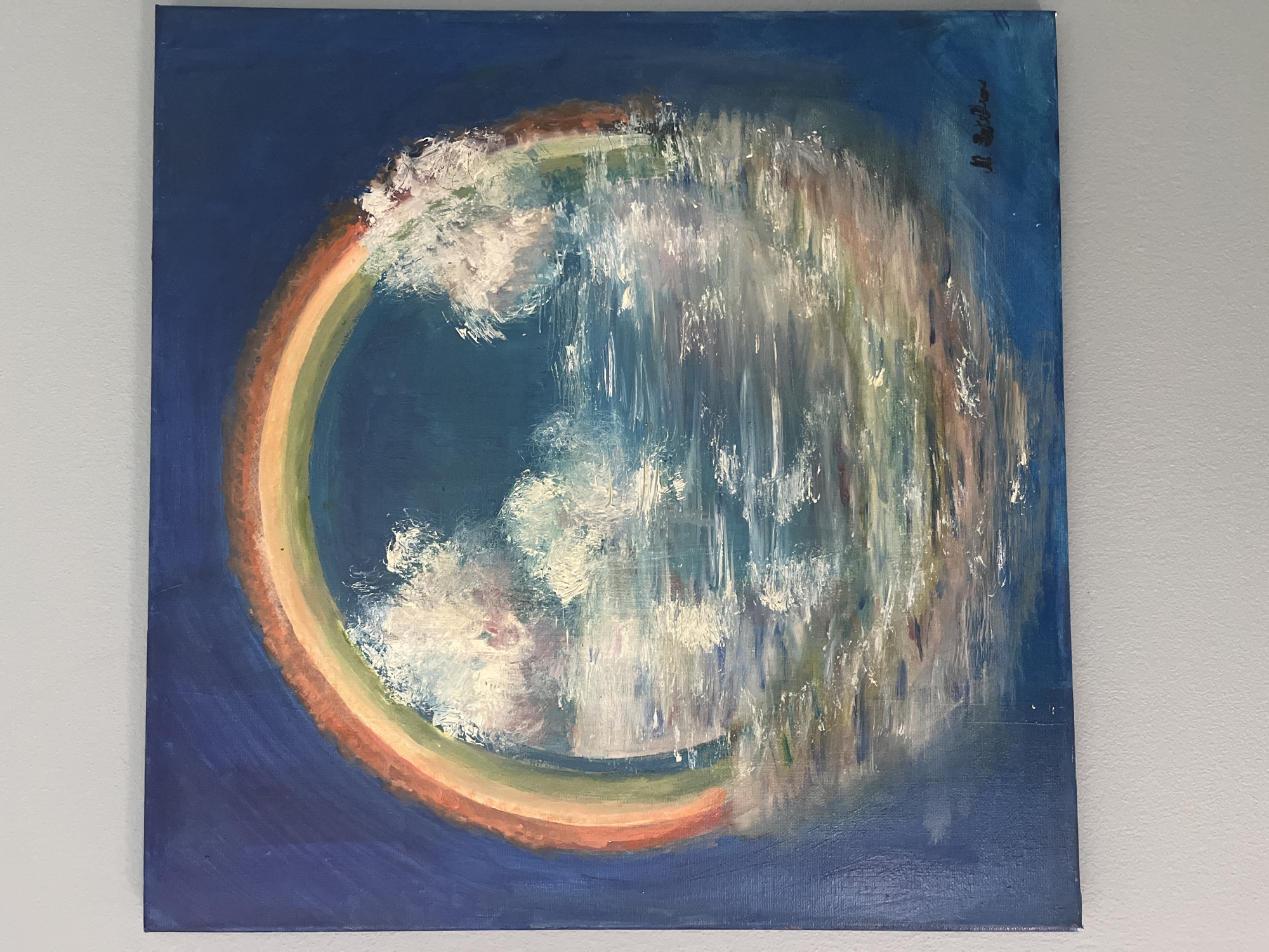 This is a photograph of an oil painting depicting a rainbow over a body of water, possibly the sea or a lake. The rainbow is a vibrant arc of colors, with red, orange, yellow, green, and blue visible. White, fluffy clouds are scattered within the arc of the rainbow, and their reflections are visible in the water below. The water itself is rendered with a variety of blues, whites, and subtle hints of other colors, suggesting movement and light. The background is a deep, dark blue, creating a contrast with the brighter elements of the painting. In the bottom right corner of the painting, there is a black, handwritten signature. The painting is hanging on a light blue wall. The location of the painting in the city of Unknown, Unknown is not ascertainable from the image.