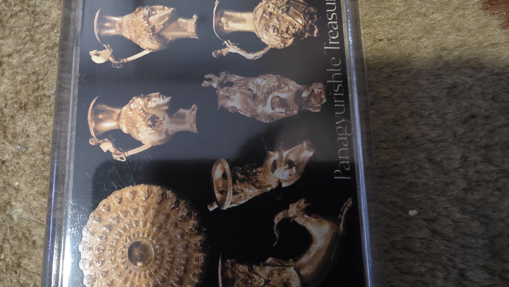 The image shows the Panagyurishte Treasure. The treasure is on display at the Regional History Museum in Blagoevgrad, Bulgaria. The treasure includes several gold vessels, including rhytons shaped like animal heads and amphorae decorated with mythological scenes.