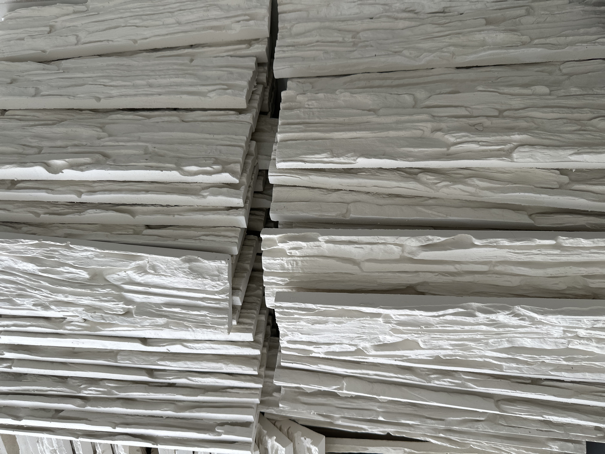 The image shows stacked white, textured stone-like panels. The panels appear to be stacked vertically in two separate columns, with a narrow gap between them. The texture of the panels suggests a rough, uneven surface, potentially mimicking natural stone. The scene is located in an unknown city and country.