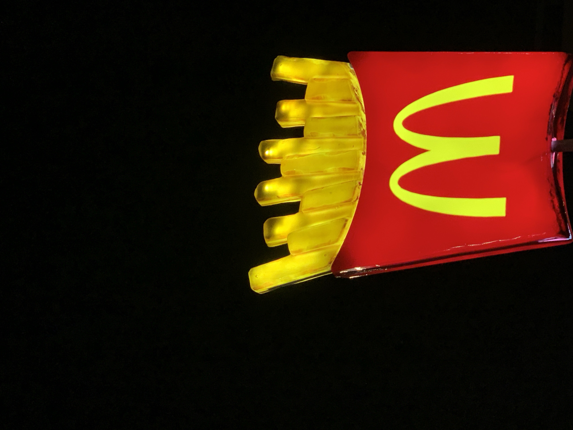 A close-up shot shows a McDonald's sign against a black background. The sign depicts a red rectangular container filled with yellow french fries on the left. A yellow "M" logo appears on the right of the container. There is no visible information that could place this scene in Tel-Aviv, Israel.