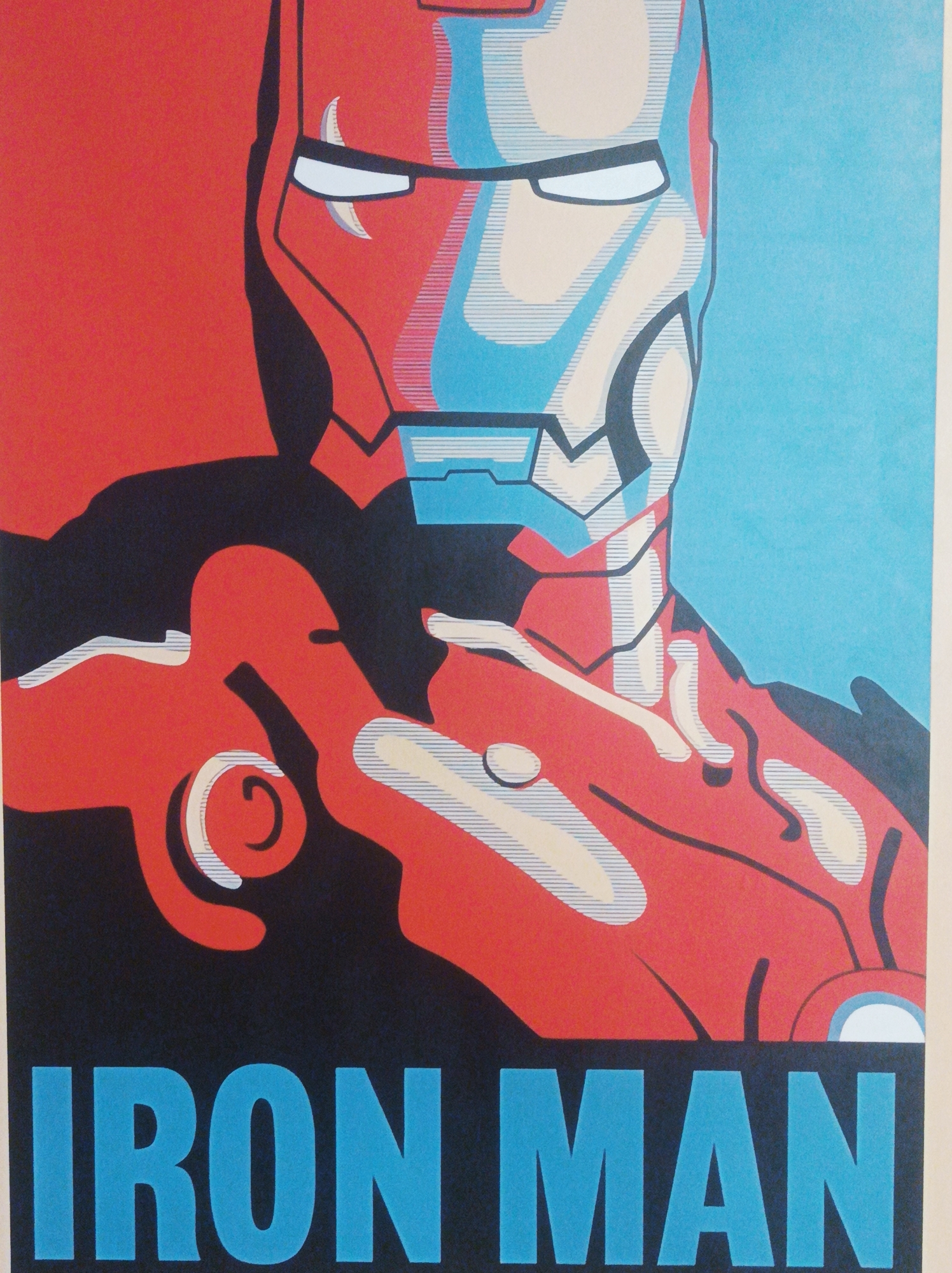 A poster depicting Iron Man. The poster is in a pop art style, with the character rendered in shades of red, blue, and black. The words "IRON MAN" are written in bold blue letters at the bottom. The background is a light blue and red. The image depicts a superhero, and it is not possible to determine any location in Porlamar, Venezuela from the information in the image.