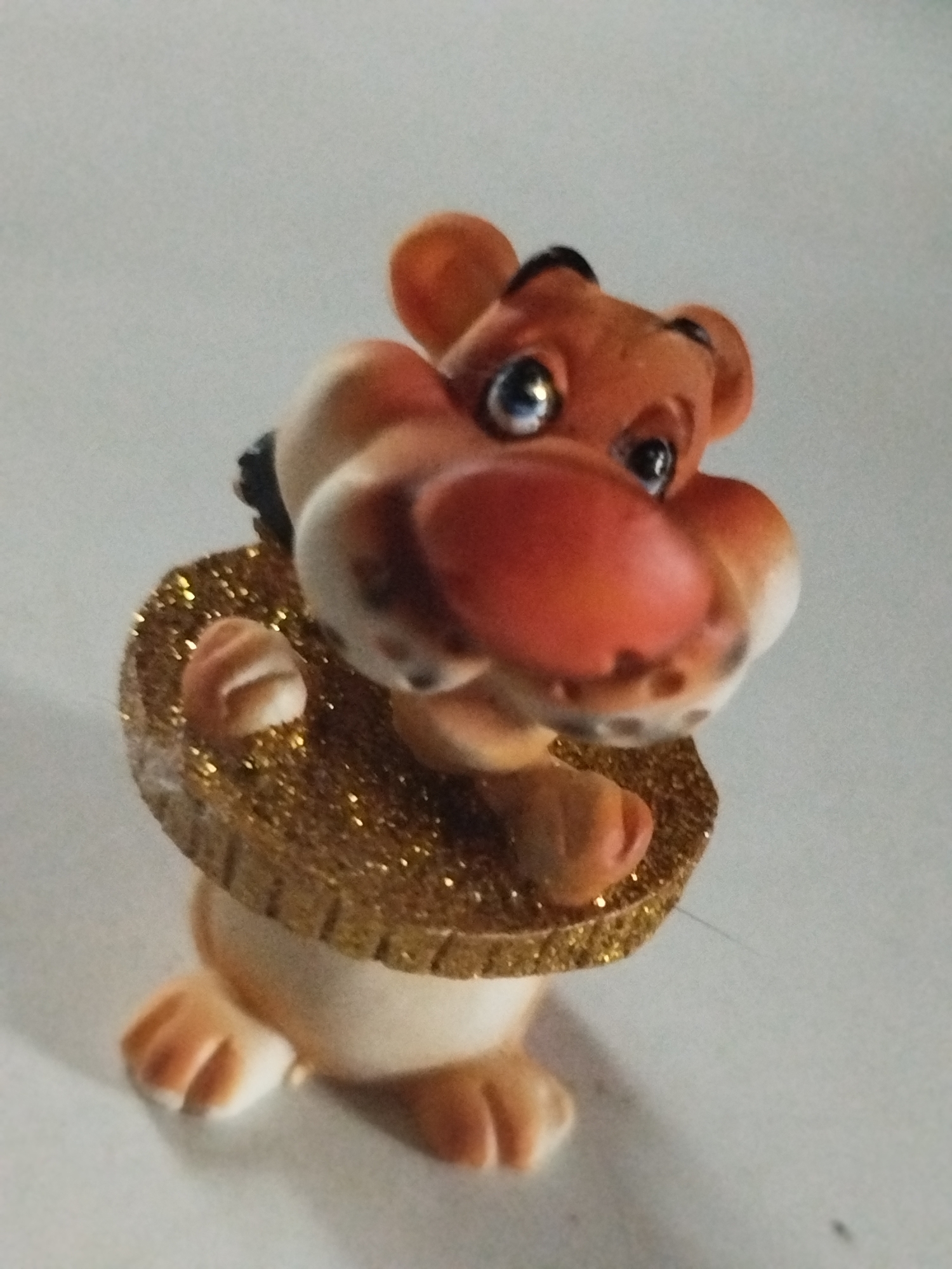 A close-up photograph shows a small, cartoonish figurine of a bear with a large, red nose and blue eyes. The figurine has a gold, glittery ring around its neck. The figurine appears to be made of ceramic or a similar material. The background is a plain, light-colored surface. The photo does not provide any information to determine that the location is Боровково, Russia.