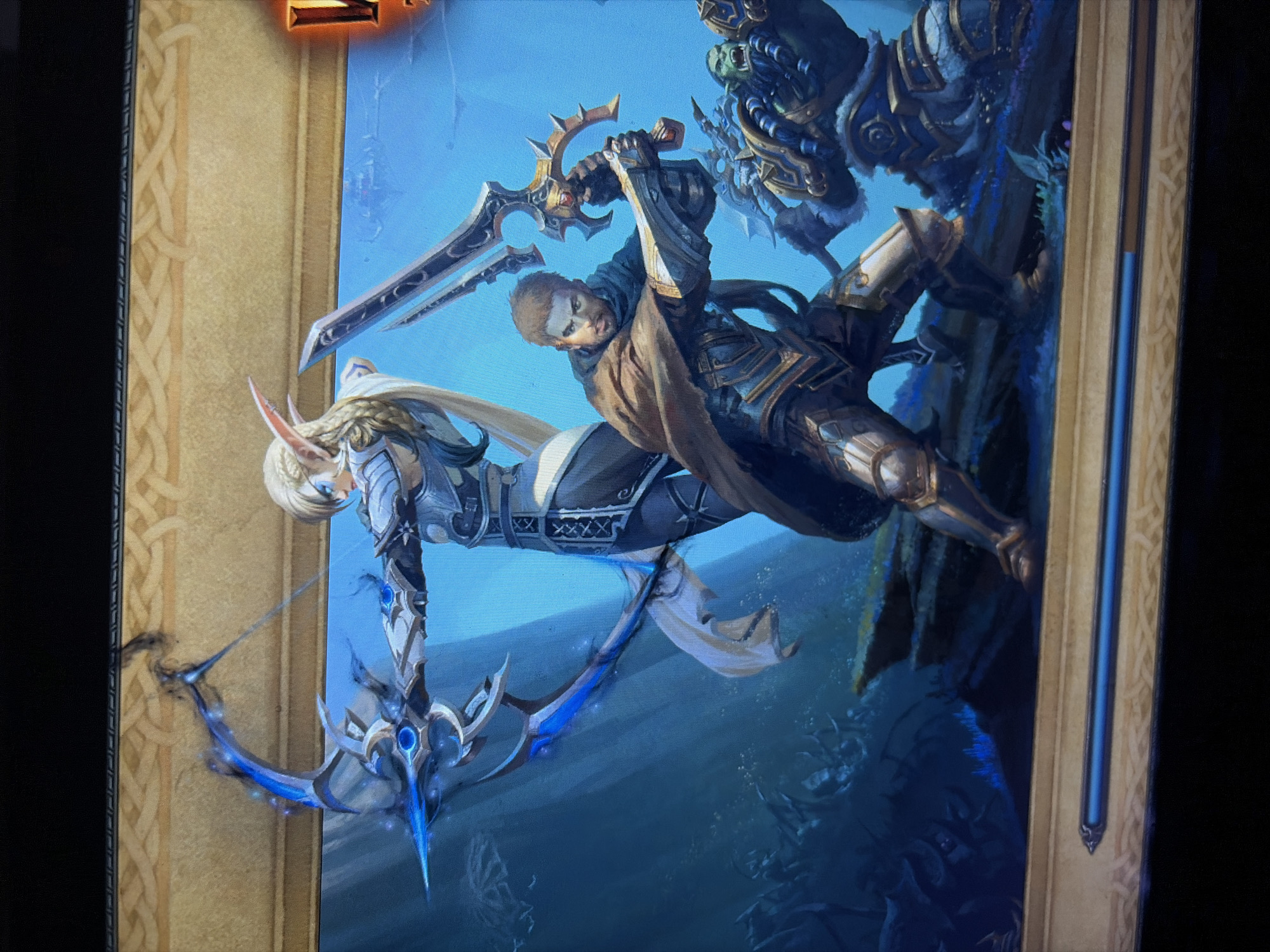 The image depicts a scene from the video game World of Warcraft, featuring three characters: a female elf archer, a male human warrior, and an orc. The elf, positioned in the center-left, is drawing a glowing blue bow, ready to fire. She wears ornate silver armor and has long blonde hair. To her right, the human warrior is in a defensive stance, holding a large sword. He is clad in dark armor with gold accents and a brown cloak. Behind and to the right of the human is a large, green-skinned orc, also in armor, appearing to be a threat. The background is a murky, blue underwater environment with rocky outcrops and shadowy figures in the depths, suggesting a battle or an exploration in a submerged location. The scene is framed by a decorative golden border with Celtic knot designs. A loading bar is visible at the bottom of the image, indicating it is a loading screen.
