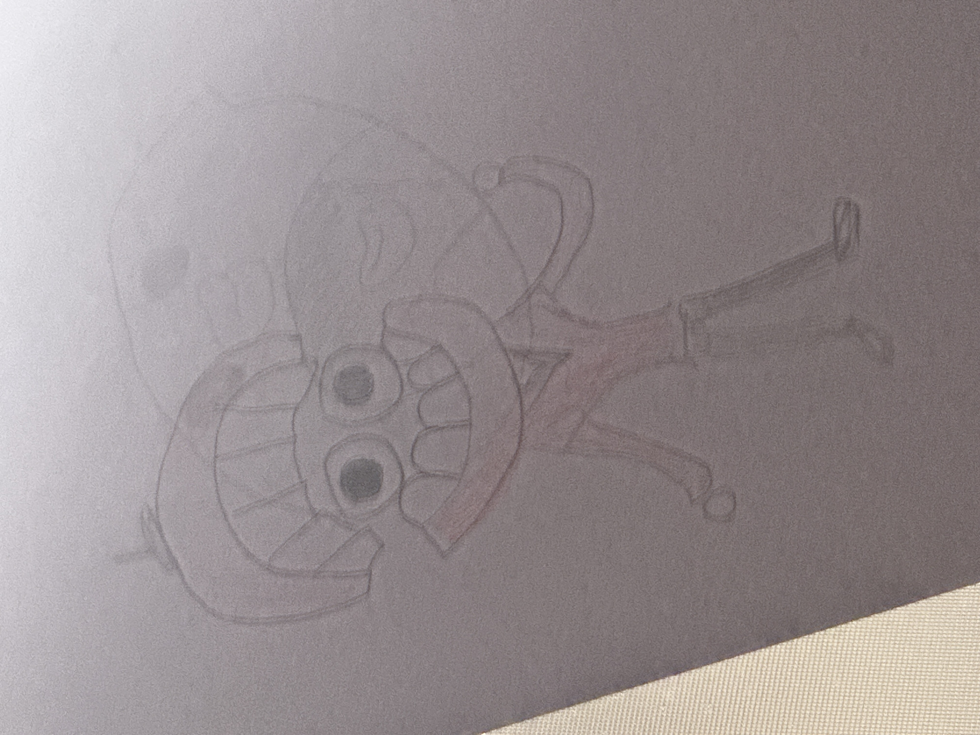 This is a sketch of a cartoon character drawn in pencil on paper. The character has a large head with a rounded helmet-like structure on top. It has two large, dark eyes and a wide, toothy grin. The body is drawn with a red shirt and dark pants. The character appears to be standing with one leg bent and the other extended. The background is plain and does not depict any specific environment. There is no information in the image to suggest a location in Kathu, Thailand.