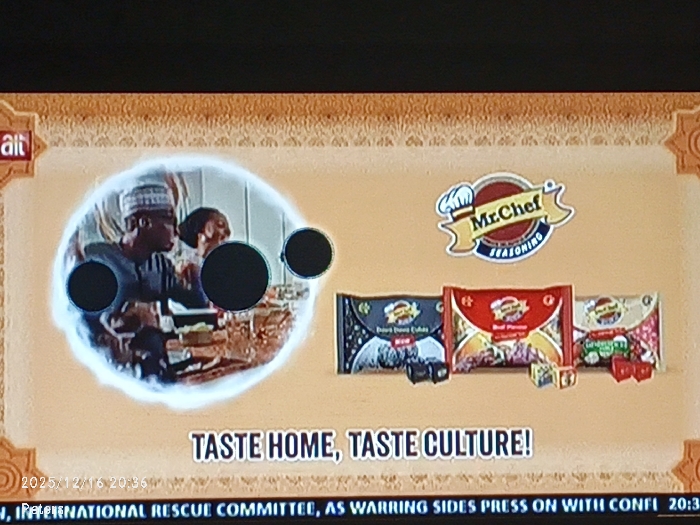 An advertisement for Mr. Chef Seasoning is displayed. It features a logo of the brand name. A circular inset shows a group of people, possibly a family, eating a meal. Below it is the tagline "Taste home, taste culture!". Three product packages, each a different flavor, are shown. There is a black one with "Dark Dawn Cubes", a red one with "Beef Stews", and one with something else, possibly "Chicken Stews." Cubes of the seasoning sit in front of each respective packet. The bottom of the screen shows a news ticker with text about the "International Rescue Committee."