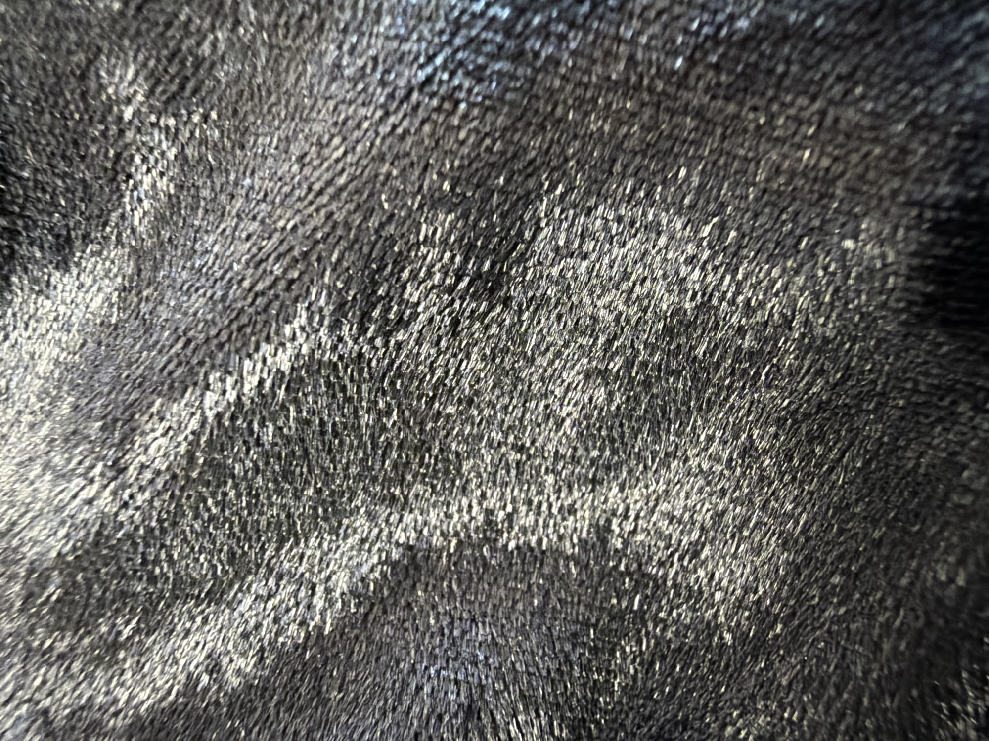The image is a close-up, abstract shot of a textured dark gray material, possibly fabric or fur, with shimmering highlights. There are no people, objects, or environmental features visible to determine a specific location. Therefore, it is impossible to provide details about the city of Minsk, Belarus, or any forensic information related to a scene.