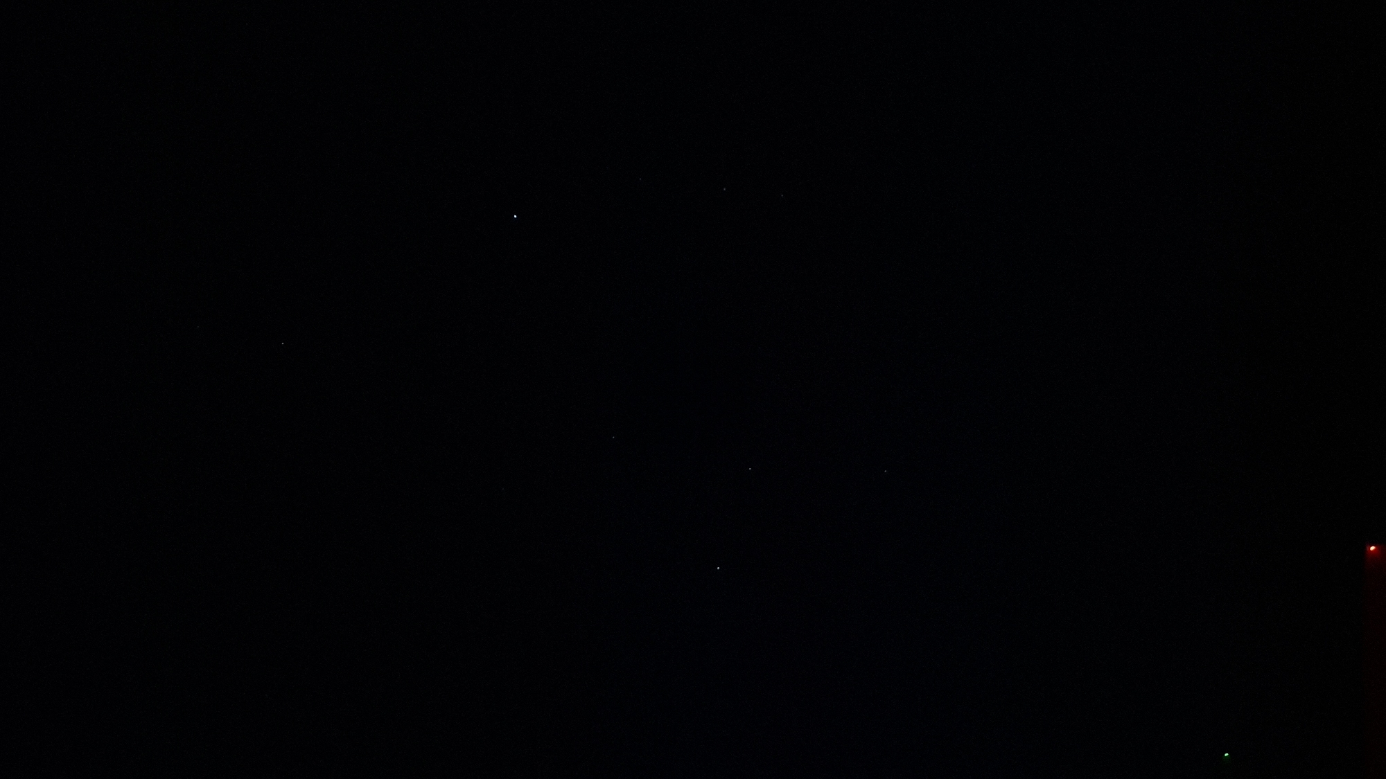 The image shows a dark night sky with a few stars visible. In the lower right corner, there are faint red and green lights. The location is Шешурга, Russia.