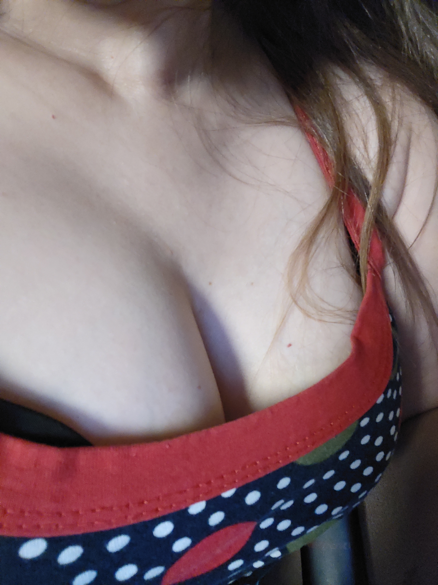 A close-up, eye-level shot focuses on the décolletage of a person wearing a patterned garment with red trim. The background is dark and out of focus, making it impossible to determine the specific location.