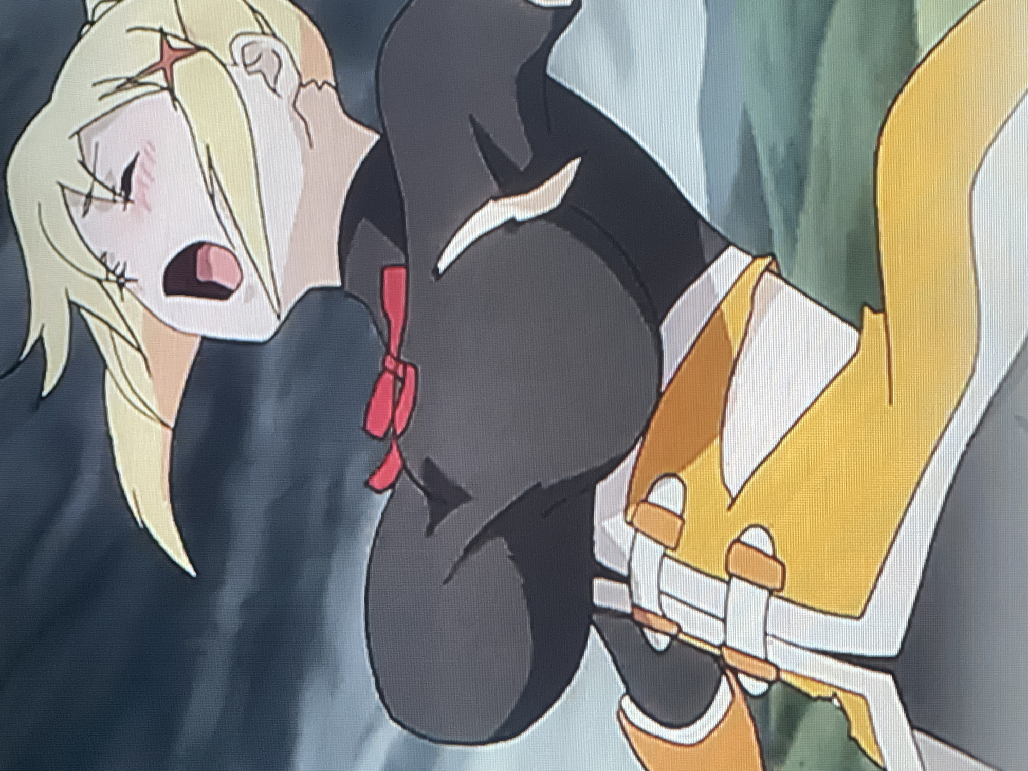 The image is a close-up shot of an anime character with blonde hair and a red star-shaped accessory. The character is wearing a black outfit with a red bow and a yellow skirt with white accents. The character's mouth is open in a scream or gasp, and their eyes are closed. The background appears to be a dark, stormy sky. There is no identifiable information in the image that places it in Batumi, Georgia, or any specific city.