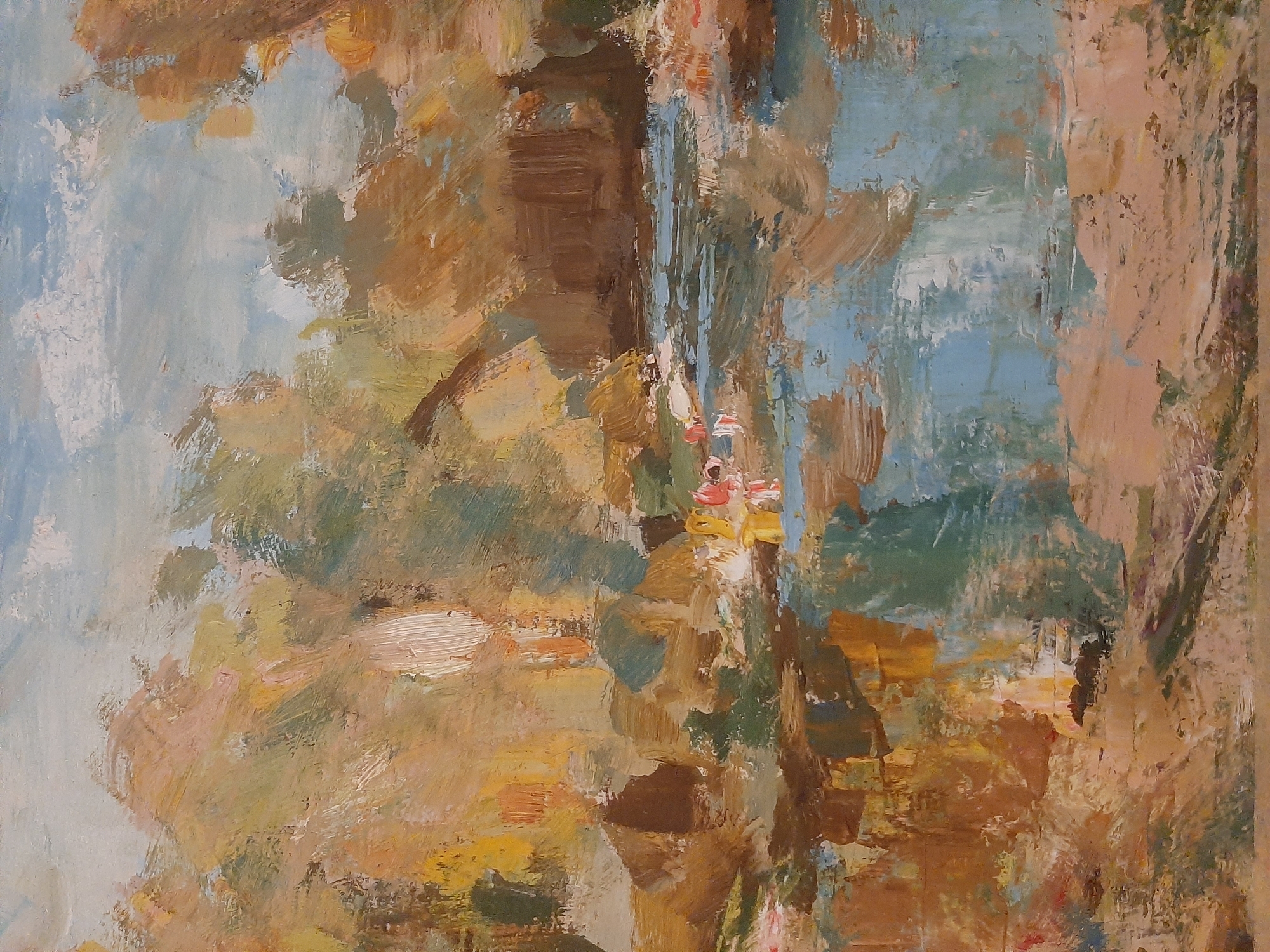 This is an impressionistic oil painting of a natural landscape. The scene depicts a body of water, possibly a river or lake, reflecting the surrounding foliage and sky. The trees are rendered in broad, loose brushstrokes of warm autumn colors, including ochre, brown, and muted green, interspersed with lighter, almost white highlights. The water exhibits a similar painterly quality, with patches of blue, grey, and brown representing the sky and the earth mirroring on its surface. In the mid-ground, there are indistinct shapes that suggest possibly small figures or boats near the water's edge, rendered with bright touches of red and yellow. The sky above is a pale blue with soft, white clouds, also depicted with visible brushwork. The overall impression is one of a peaceful, natural setting captured with a focus on light and color rather than precise detail.