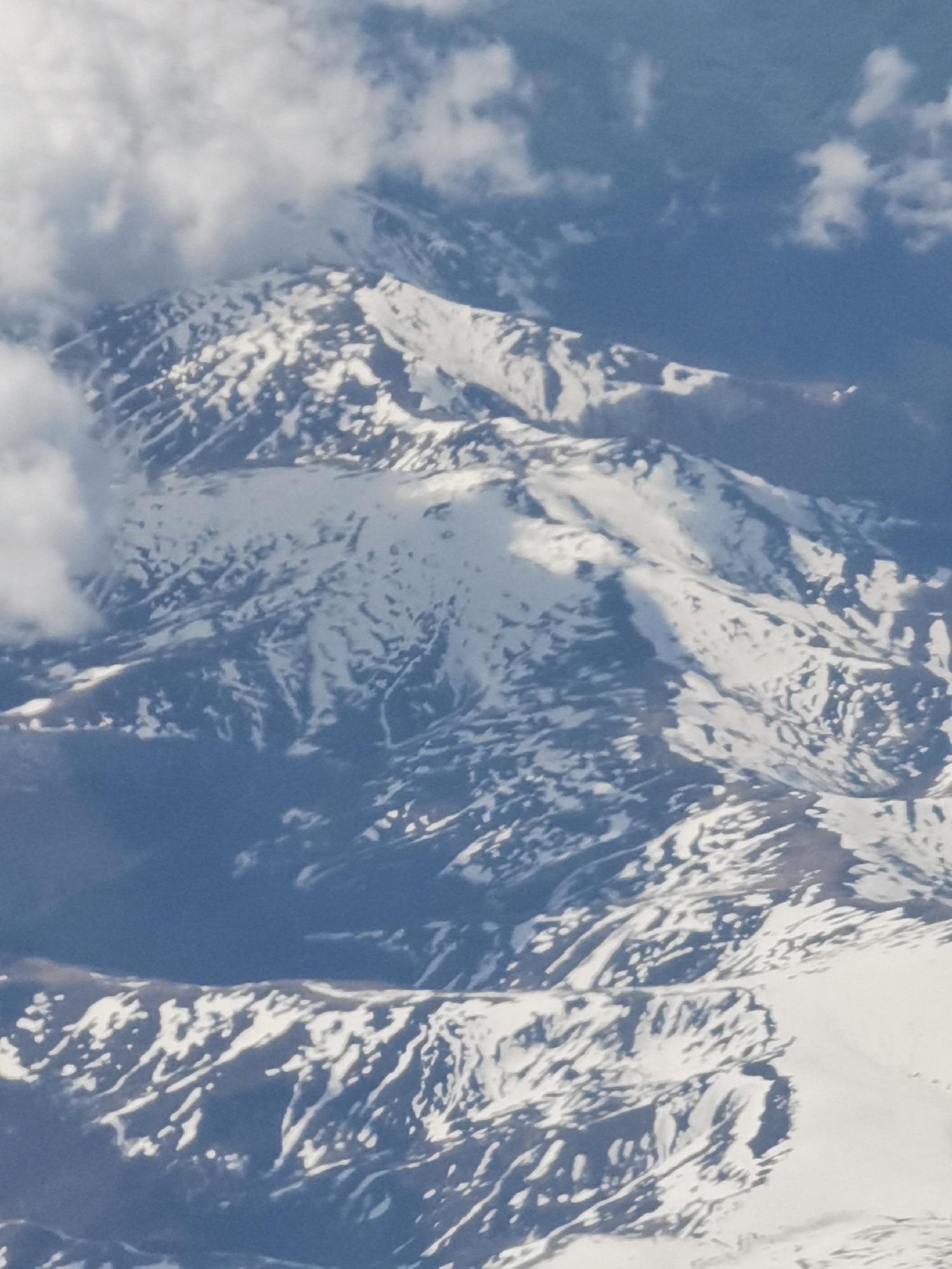 The image shows a mountainous region partially covered in snow. Some clouds are present near the peaks. There is no indication of it being located in or near Varna, Bulgaria.