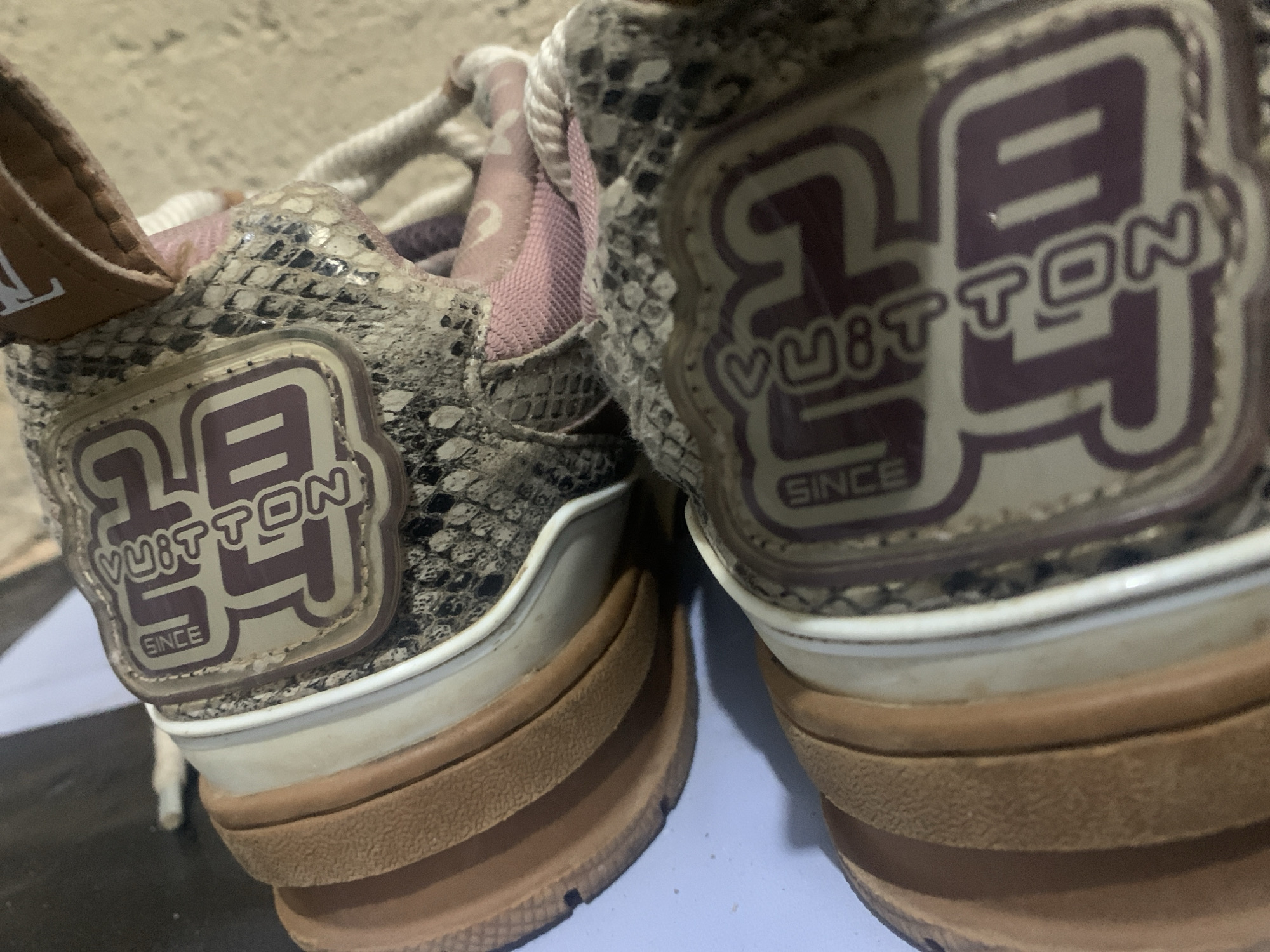 The image shows a close-up view of two Louis Vuitton sneakers with a snakeskin pattern and a prominent "LV" logo with the word "VUITTON" and "SINCE" below it. The sneakers appear to be on a light blue surface. The specific location in Rafin Par, Nigeria, cannot be determined from the image.