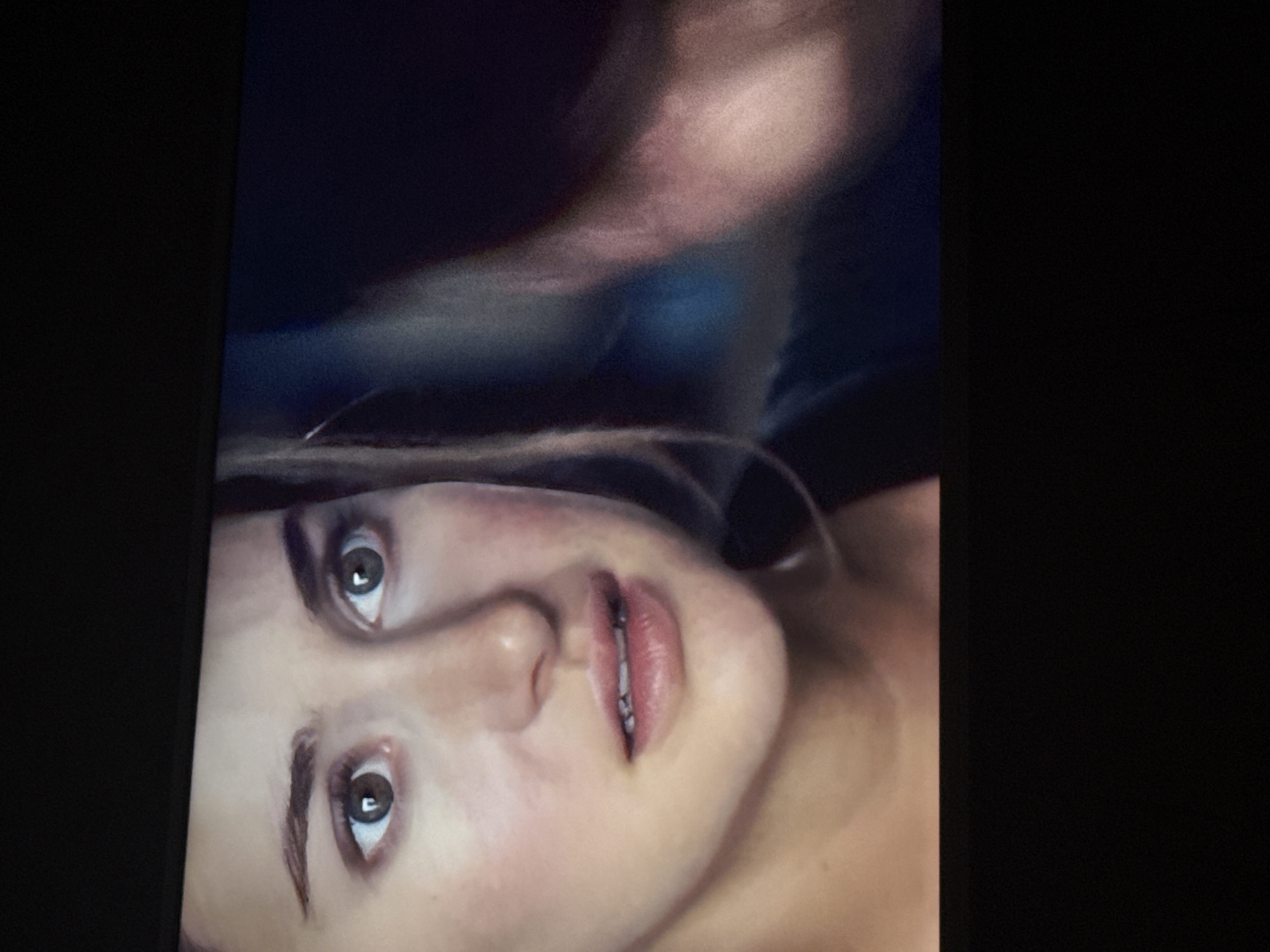 A close-up shot depicts a woman's face with an expression of distress or surprise. Her eyes are wide, and her mouth is slightly open. The skin appears pale, with some redness or discoloration on the cheeks and around the eyes. Some stray strands of light-colored hair are visible. The upper portion of the image shows a blurry, possibly human form, with an indistinct background. There is no evidence to establish the location in Mytishchi, Russia.