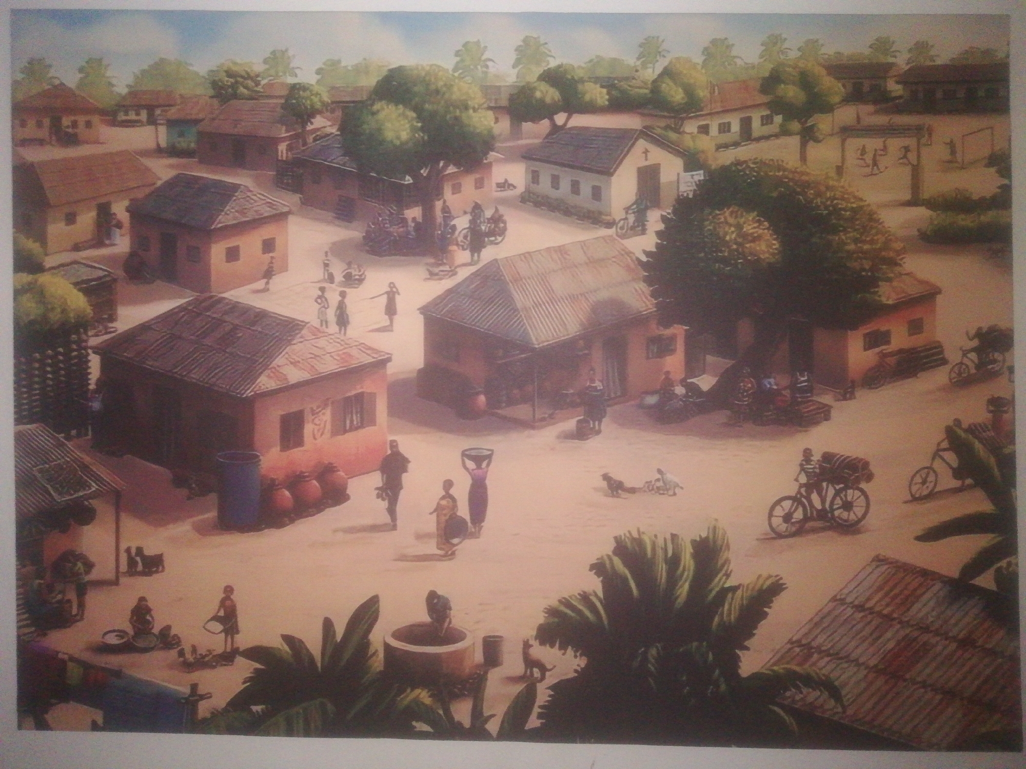 The image depicts a village scene, reminiscent of Ikorodu, Nigeria. Several mud-brick houses with corrugated metal roofs are scattered around a sandy, open area. People are engaged in various activities: some are cooking, others are carrying water or goods, and children are playing. Bicycles are present, some laden with goods. There is a well and a church in the village. Trees provide shade throughout the scene. The overall atmosphere is one of a bustling, close-knit community.