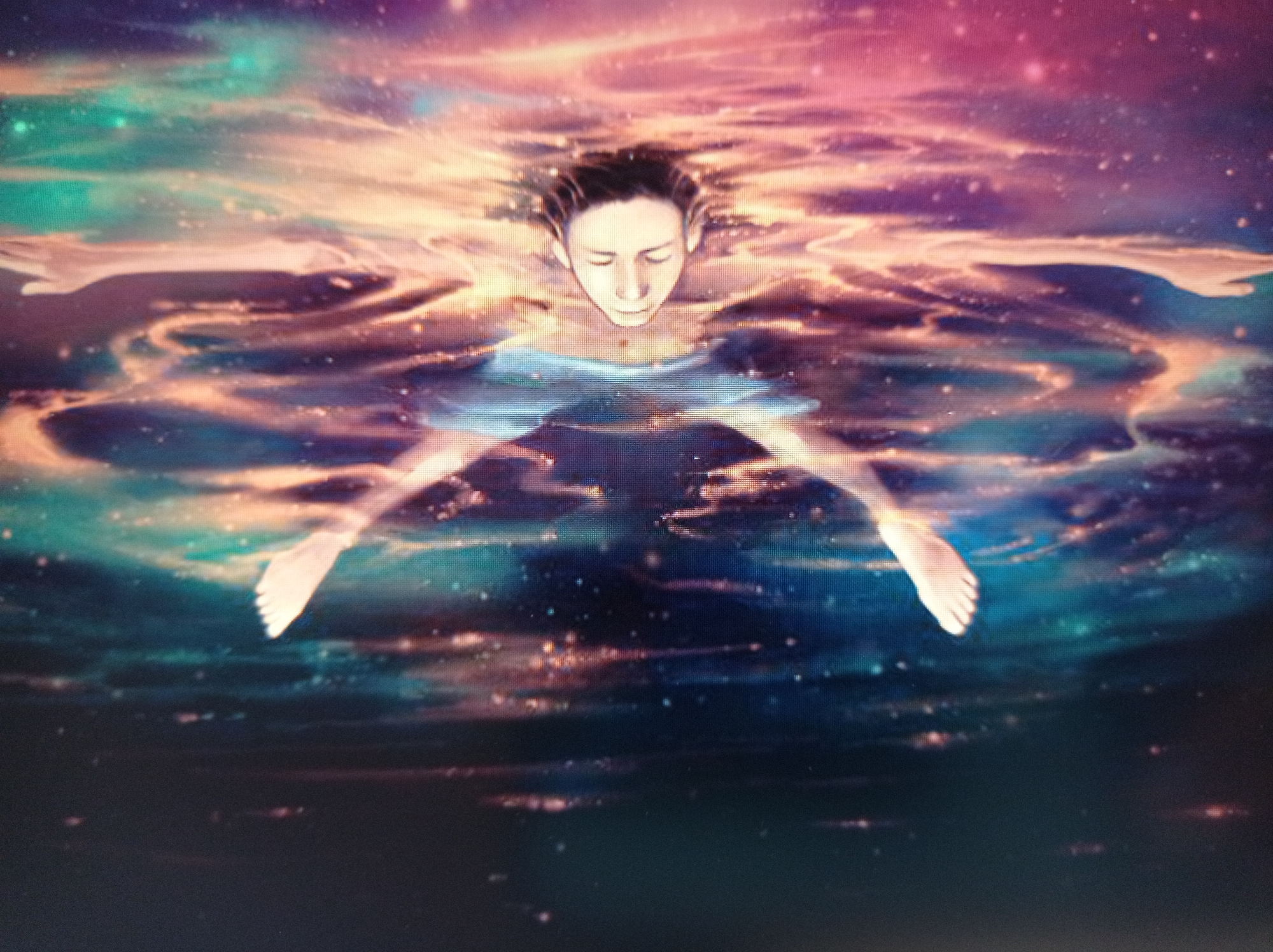 The image depicts a person floating on their back in a surreal, cosmic-like body of water. The water exhibits swirling patterns of vibrant colors, including deep blues, purples, pinks, and oranges, interspersed with twinkling white speckles that resemble stars. The person's face is tilted upwards, eyes closed, with wet hair fanned out around their head. Their arms and legs are spread wide, creating a star-like silhouette. The overall impression is one of deep tranquility and immersion in a dreamlike or otherworldly environment. There is no discernible connection to Mukachevo, Ukraine, as the scene is abstract and fantastical.