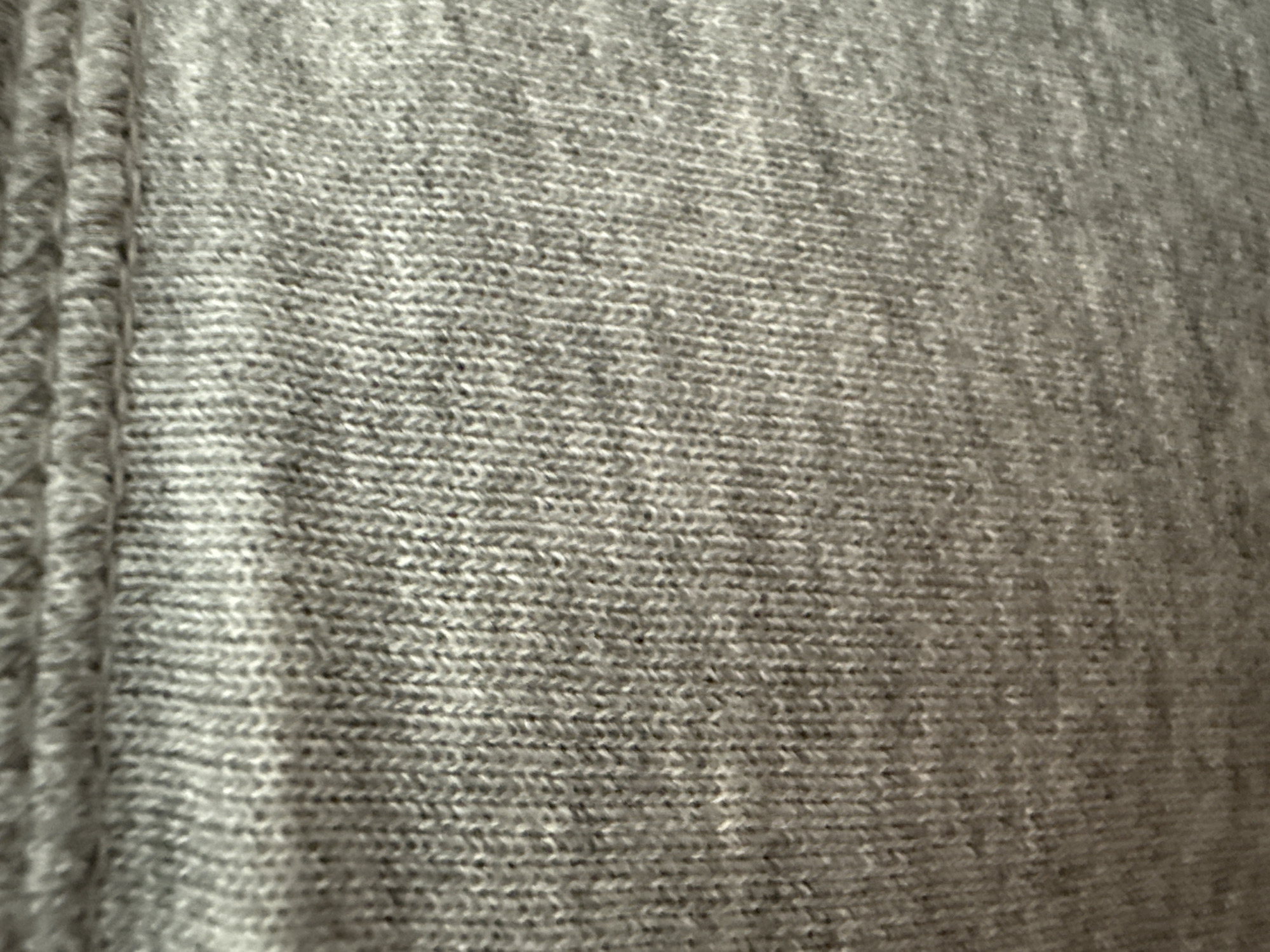 The image shows a close-up of gray knitted fabric. There is a seam visible on the left side of the frame. The knitting pattern is visible throughout the rest of the image. There are no people, subjects, objects, actions, interactions, or environmental contexts beyond the fabric itself. The location of Lovech, Bulgaria, is not relevant as the image only shows a piece of fabric.