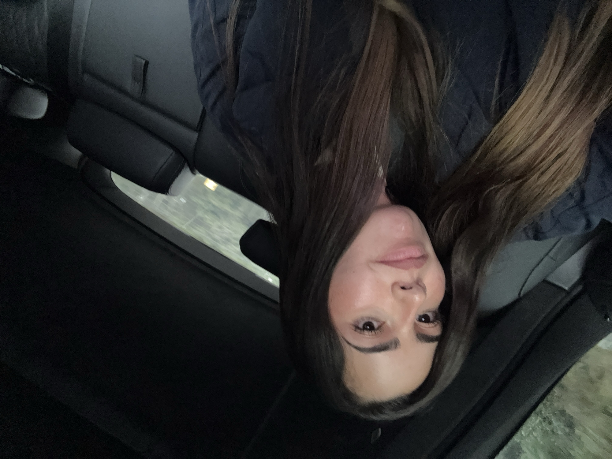 A woman with long, light-brown hair is inside a car. She is wearing a navy-blue, quilted jacket. The background is blurry and indistinct. The location of Río Frío de Juárez, Mexico, cannot be determined from the image.