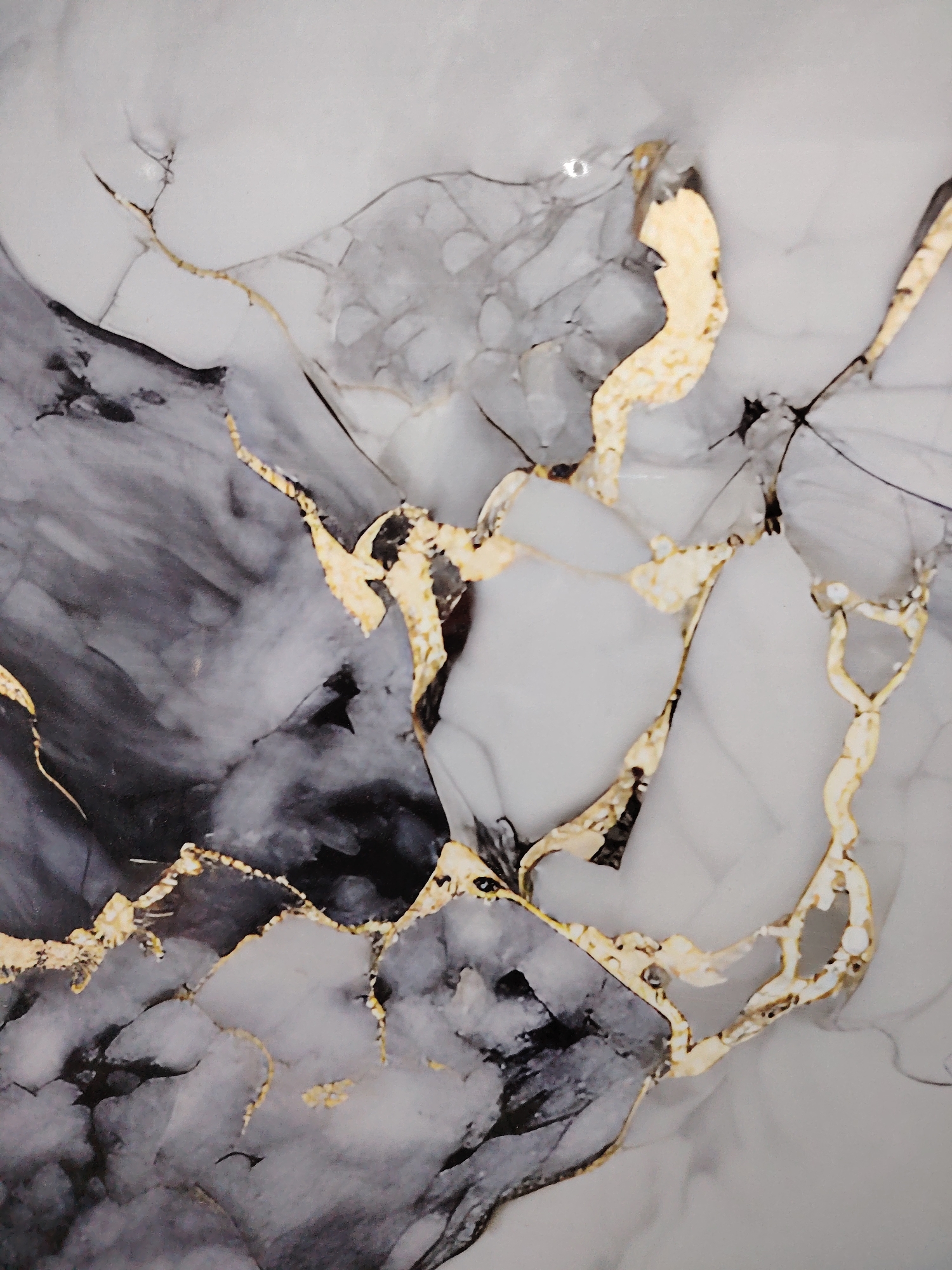 The image displays a close-up view of a marble-like surface with prominent veins of gold and dark gray. The pattern is abstract and resembles natural stone with irregular, branching lines. There are no people, objects, or environmental features that would indicate a specific location in the city of Pitnak, Uzbekistan.