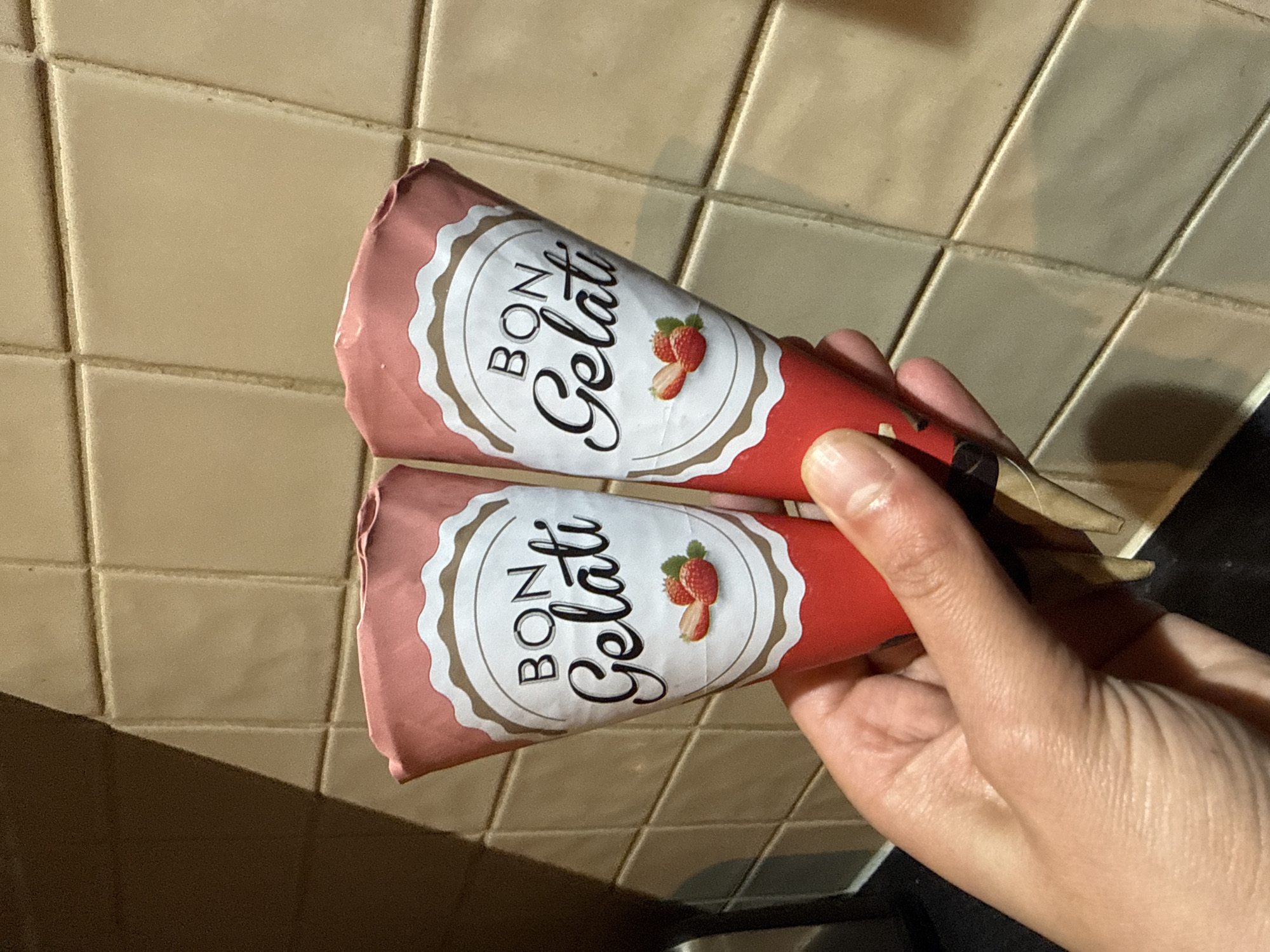 A hand holds two pre-packaged ice cream cones, with "Bon Gelati" printed on the pink and red packaging. The background is a tiled wall. The location, Great Yarmouth, UK, is inferred from the availability of this brand.