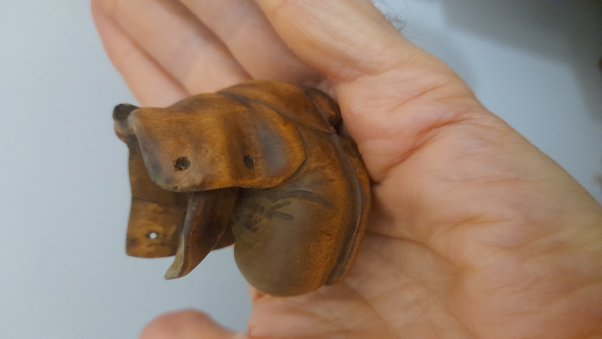 A person is holding a small, wooden carving of an elephant in their hand. The carving is brown and appears to be detailed. There is no indication of location in the city of Saint Petersburg, Russia or any other city.