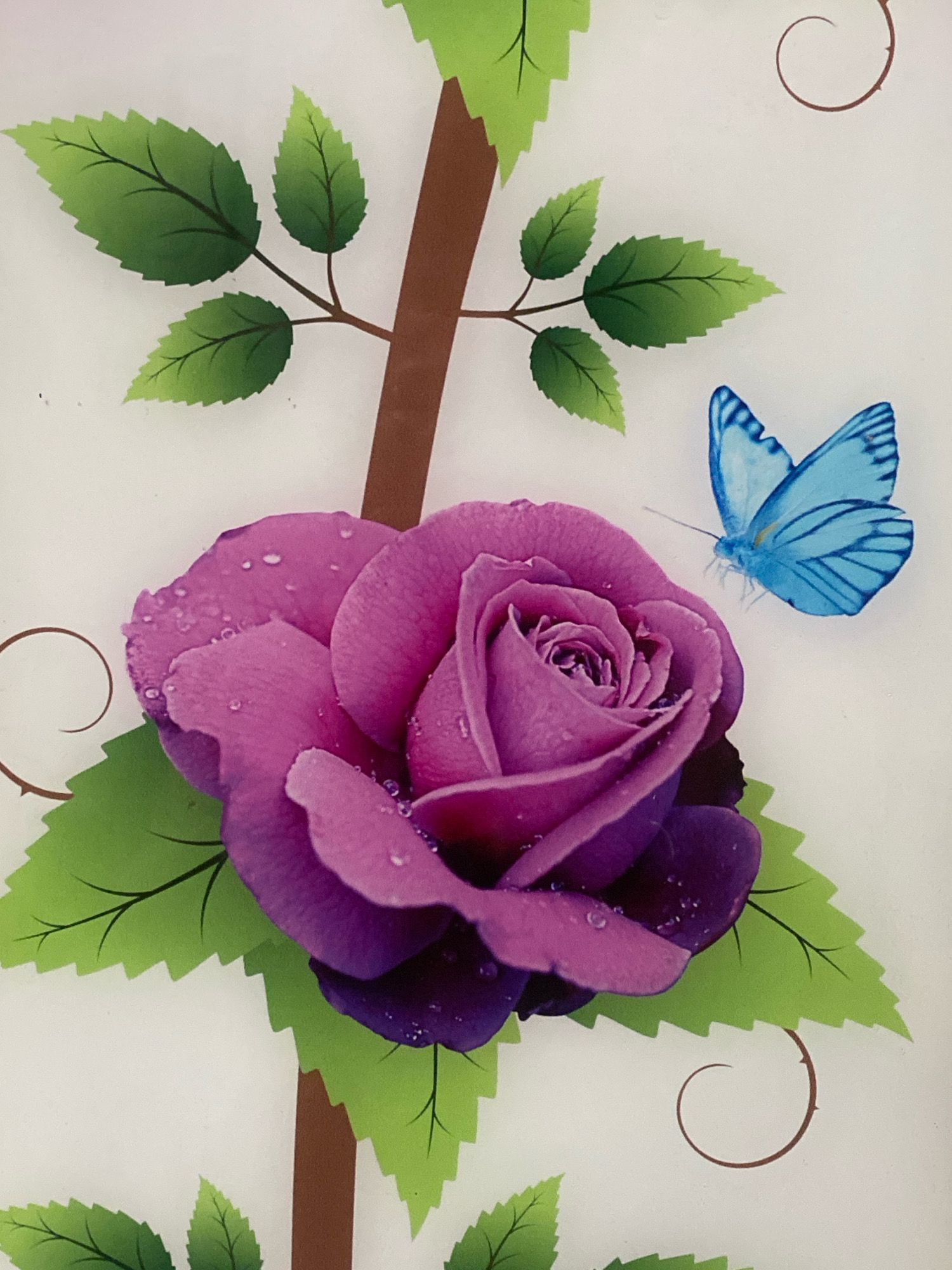 The image is a close-up, high-angle shot of a decorative illustration on a white background. The illustration features a large, vibrant purple rose with water droplets on its petals. To the right of the rose, a bright blue butterfly with detailed wing patterns is depicted in flight. The rose is positioned on the left side of the frame, with its stem and leaves extending upwards and outwards. The leaves are a bright green with serrated edges and dark veins. A brown, tree-like trunk element is visible vertically behind the rose and leaves. Small, brown, spiral decorative elements are scattered on the white background. There are no people or any elements that would suggest a specific location in Batam, Indonesia. The scene is purely illustrative and decorative.