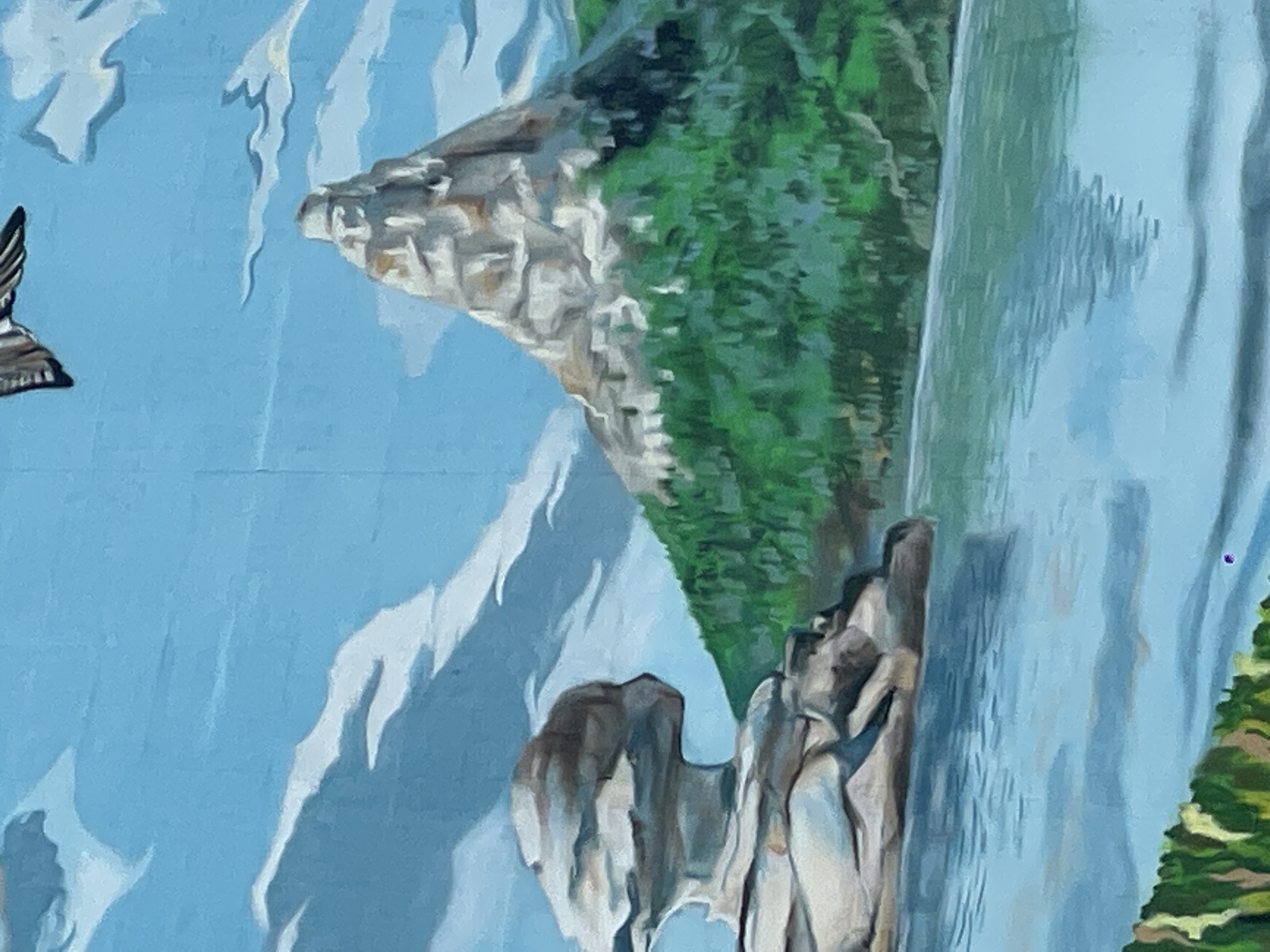 The image is a partial view of an outdoor mural depicting a landscape with a waterfall, rocky cliffs, and greenery. A bird is depicted flying in the upper left corner. The background is a light blue, possibly representing the sky, and there are white accents that could be clouds or snow-capped mountain peaks in the distance. The mural appears to be located in Kokshetau, Kazakhstan, as it is part of the prompt.