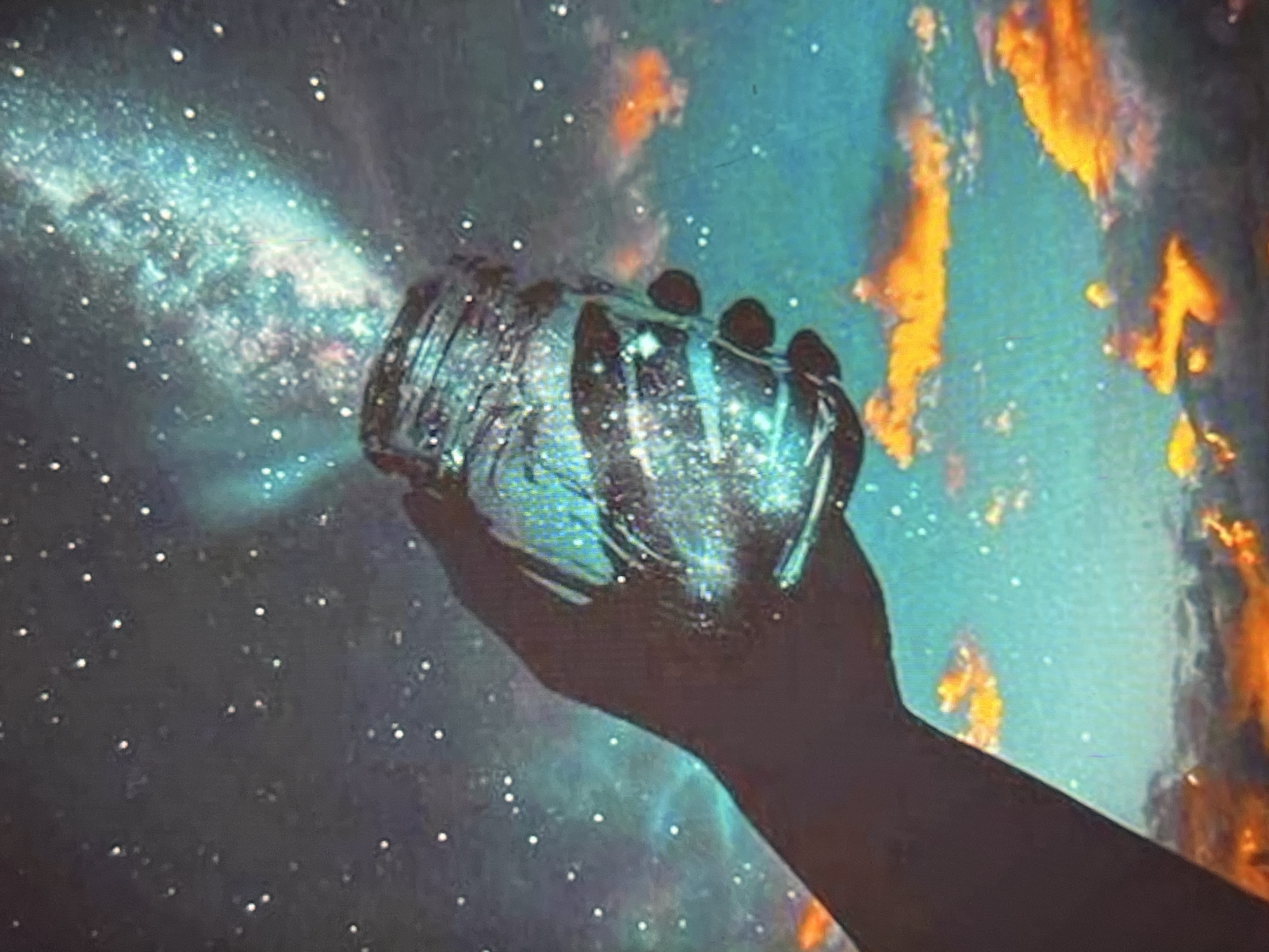 In an outdoor, ethereal landscape, a hand is shown holding a glass jar. The jar is filled with a swirling, luminous galaxy, with stars and nebulae appearing to erupt from its opening and spill into the sky. The background is a vibrant, star-filled night sky with scattered, glowing orange clouds that resemble a sunset. The overall scene evokes a sense of magic and wonder, with the jar acting as a vessel for the cosmic spectacle.