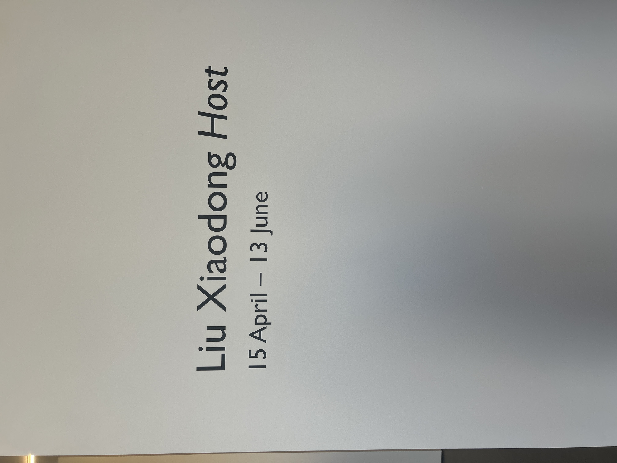 The image shows a sign advertising an event. The text on the sign reads "Liu Xiaodong Host" followed by the dates "15 April - 13 June". It is not possible to determine the location within Los Angeles, United States of America or any additional details about the scene.