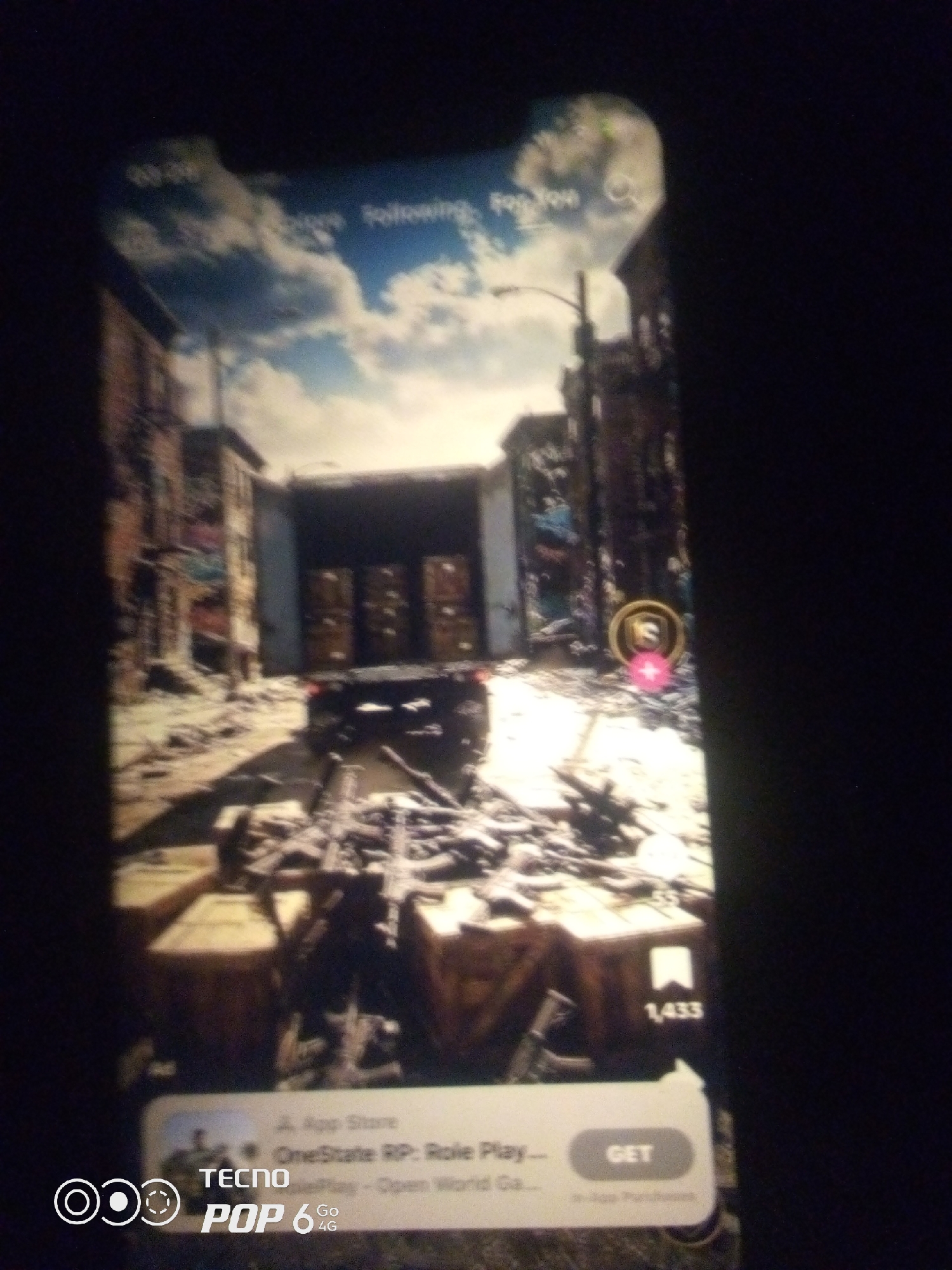 The image displays a mobile phone screen showing a video game or application interface. The game appears to be set in a post-apocalyptic urban environment with buildings, debris, and a truck. Text overlays indicate app store information, game title "OneState RP: Role Play—Open World Ga...", and a "GET" button. There are also icons for likes and shares. The bottom of the phone screen displays the "TECNO POP 6 Go 4G" branding. The image does not contain any visual information that would allow for the determination of its location in Howayi, Nigeria or any other specific geographic location.