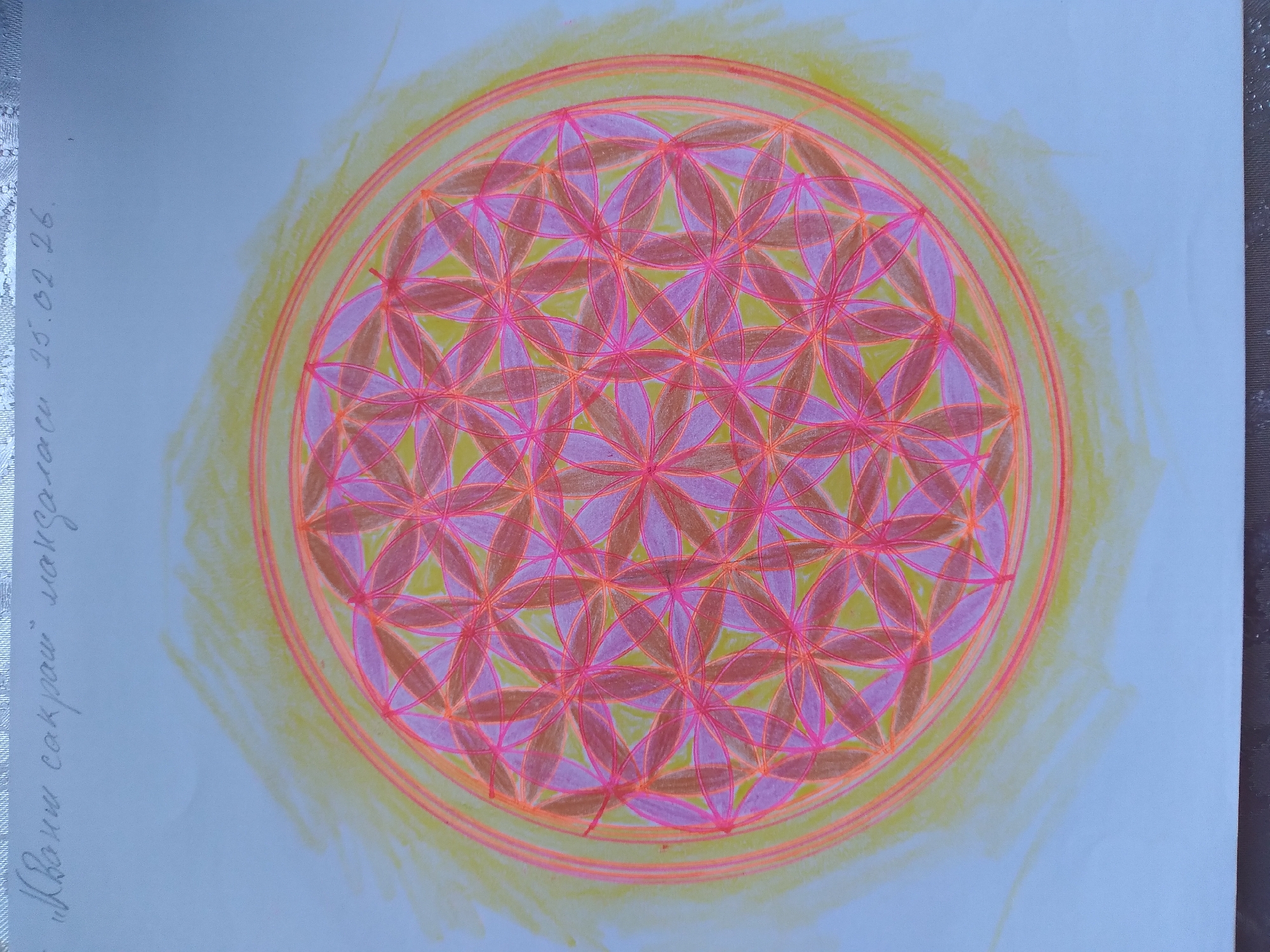 The image displays a drawing of the Flower of Life symbol, rendered in shades of yellow, orange, pink, and purple. The symbol is enclosed within concentric circles, and a yellow aura extends outwards. Above the drawing, there is handwritten text in what appears to be Cyrillic script, followed by a date: "15.02.26." The image does not provide any information or visual cues related to the city of Baki, Uzbekistan.