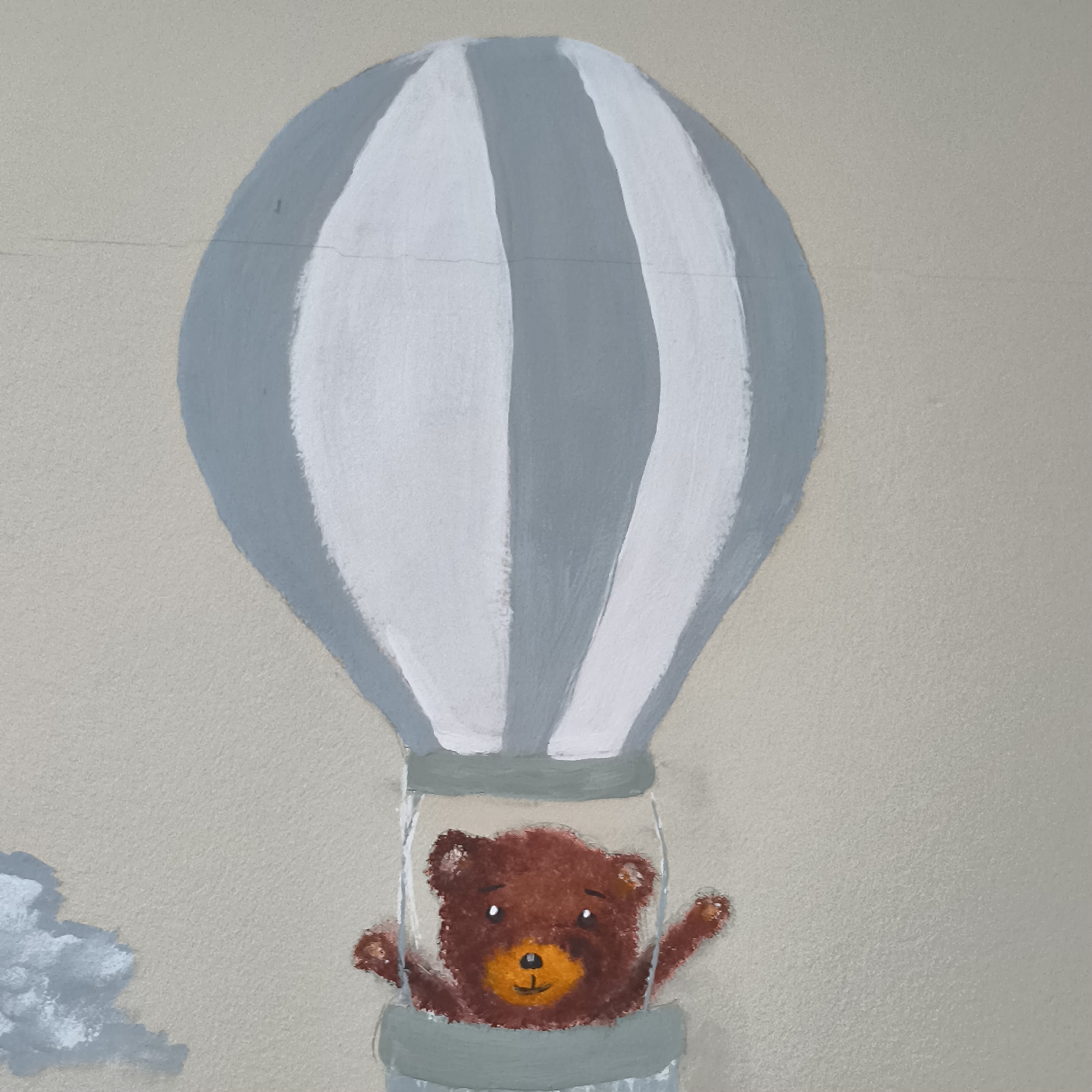 An outdoor mural depicts a cartoon brown bear in a hot air balloon. The bear is looking forward with a friendly expression, with its right arm raised as if waving. The hot air balloon has grey and white stripes. To the left of the balloon, a painted cloud is visible. The mural is painted on a textured, light brown wall, which appears to be an exterior wall. The image does not provide any information about its specific location in Varna, Bulgaria.