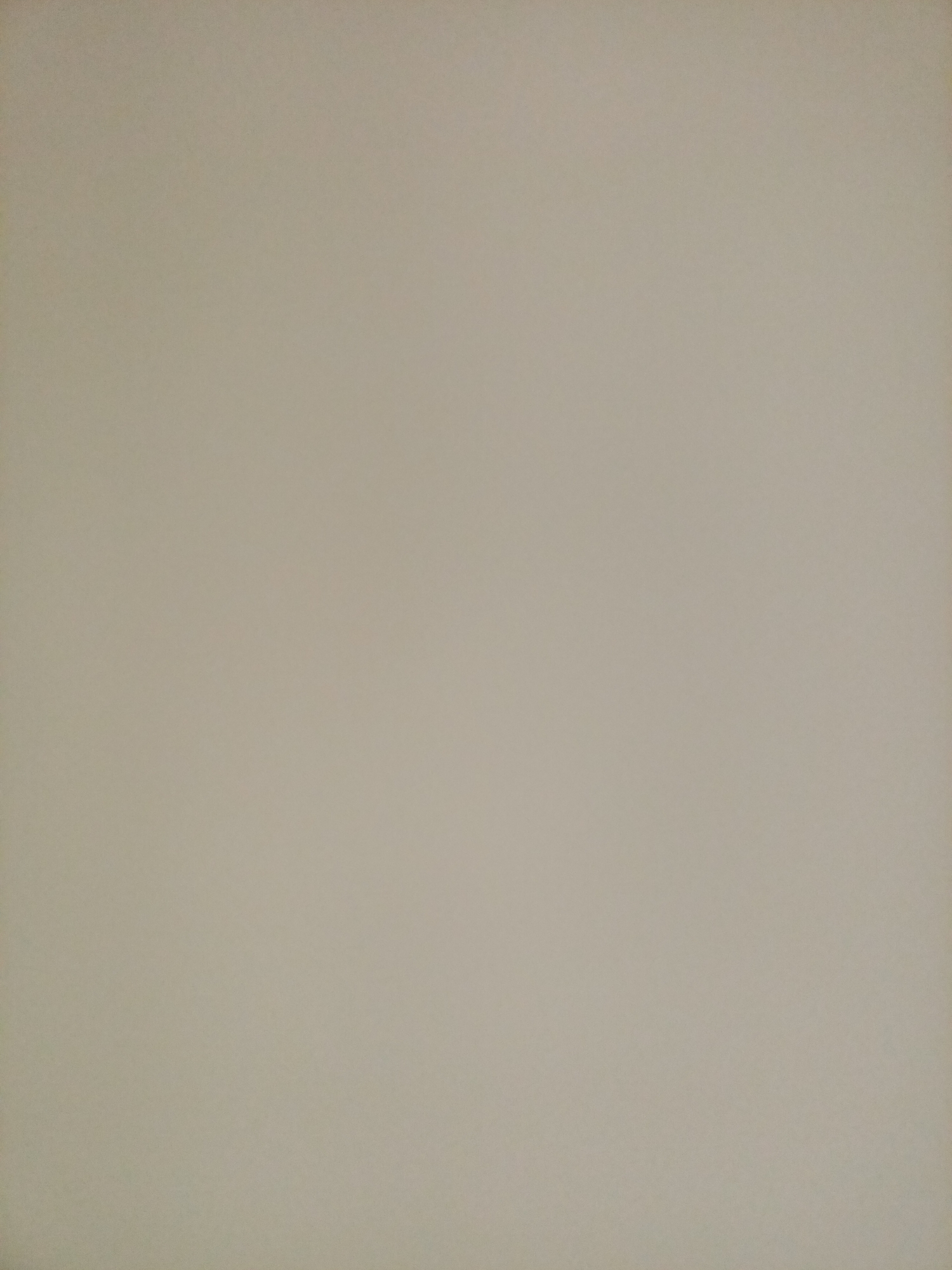 The image is a plain, neutral background, appearing to be a wall or a piece of paper. The color is a light, desaturated beige or taupe. There are no discernible objects, people, or actions within the frame. The texture is slightly grainy, suggesting a matte finish. The lighting is even, with no strong shadows or highlights. This image does not contain enough information to determine its location in Rostov-on-Don, Russia, or any other specific setting.