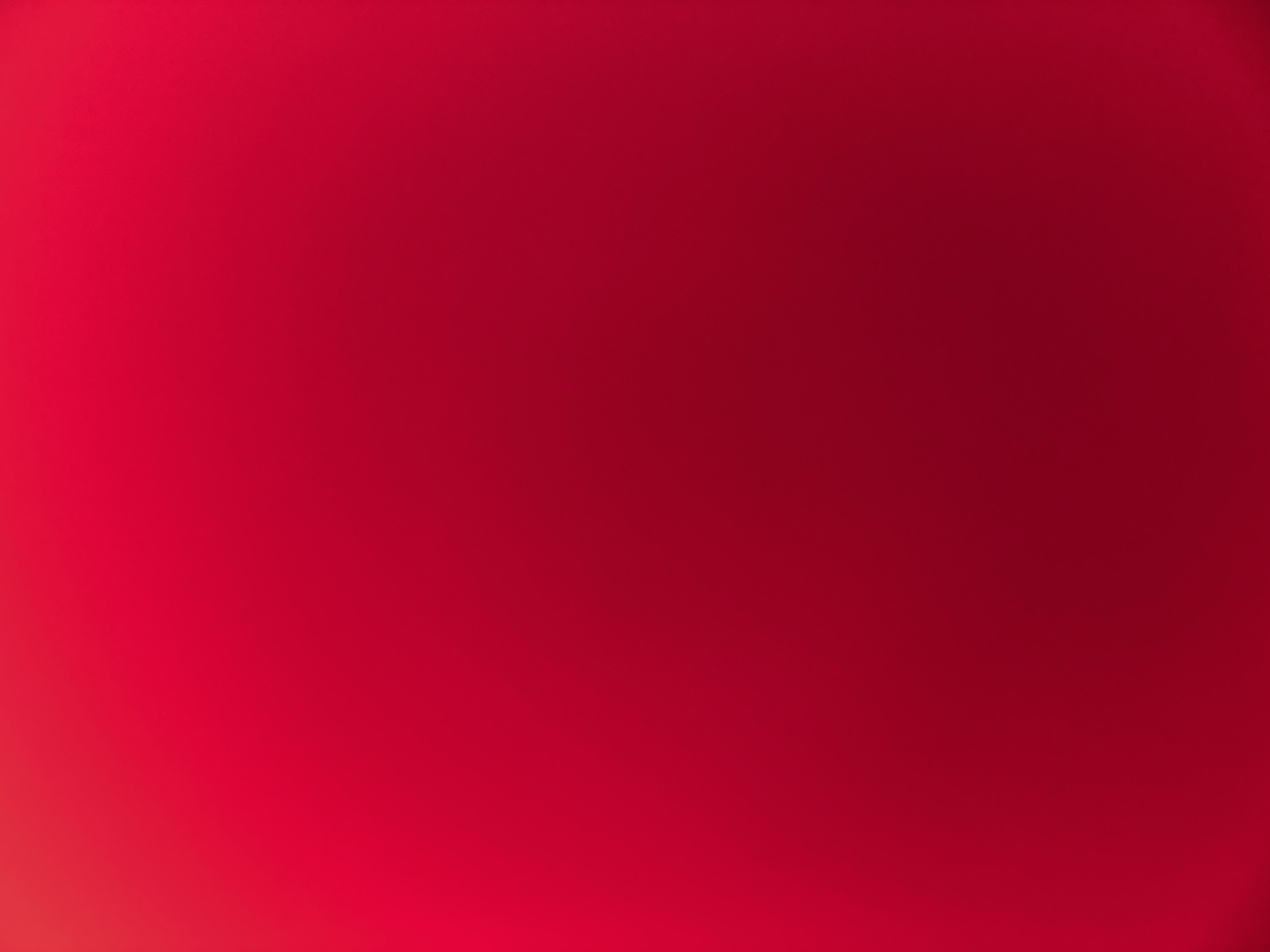 The image is a close-up, out-of-focus shot of a solid red surface. There are no discernible objects, people, actions, interactions, or environmental details present. The lighting creates a gradient effect, with the top of the image appearing brighter and the bottom darker. There is no information within the image to suggest a location in Belgrade, Serbia, or any other specific place.