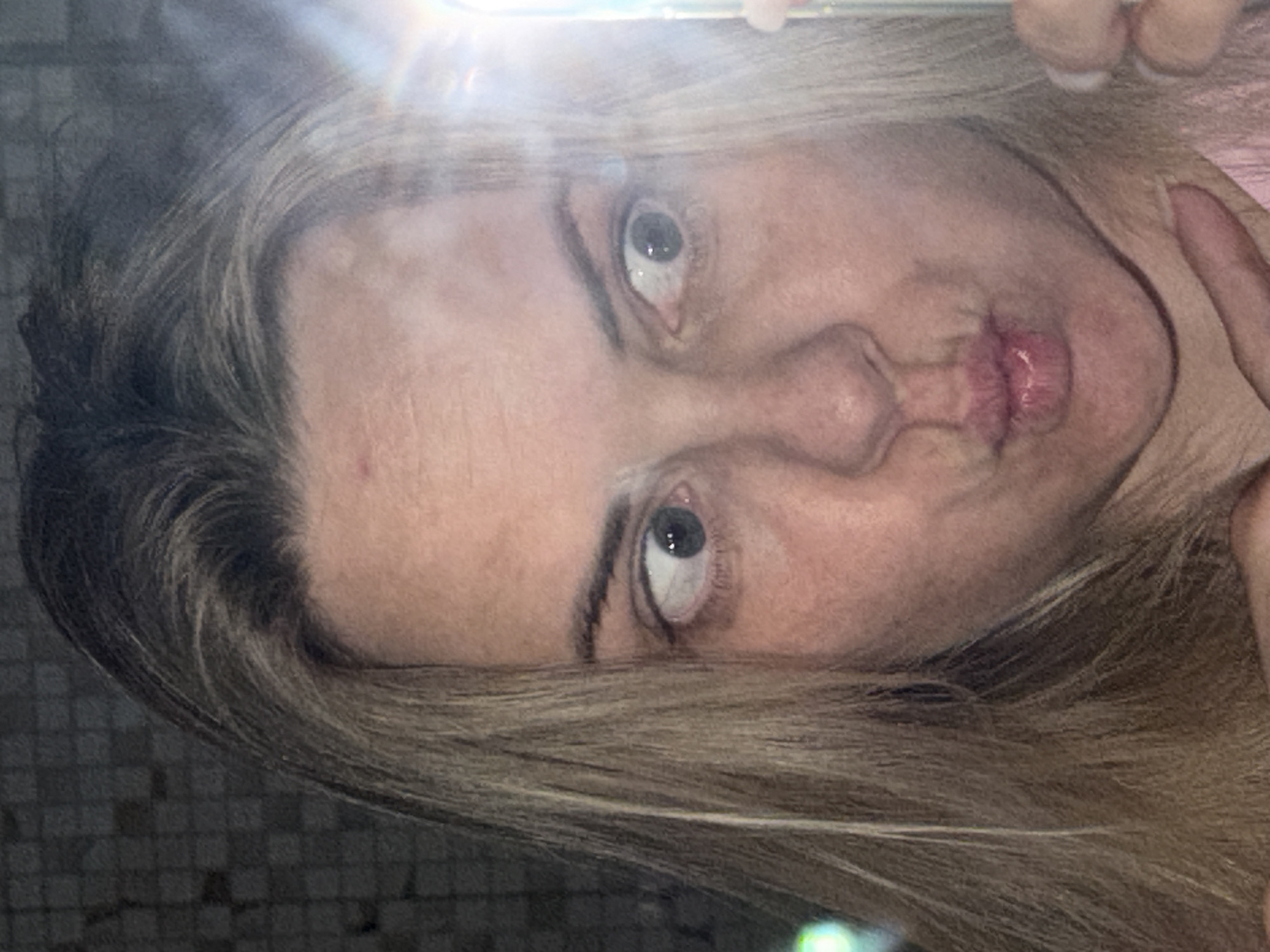 A close-up selfie of a fair-skinned woman with light blonde hair making a duck face. The background is a dark, tiled wall. No clear evidence exists to support the image being located in Votkinsk, Russia.