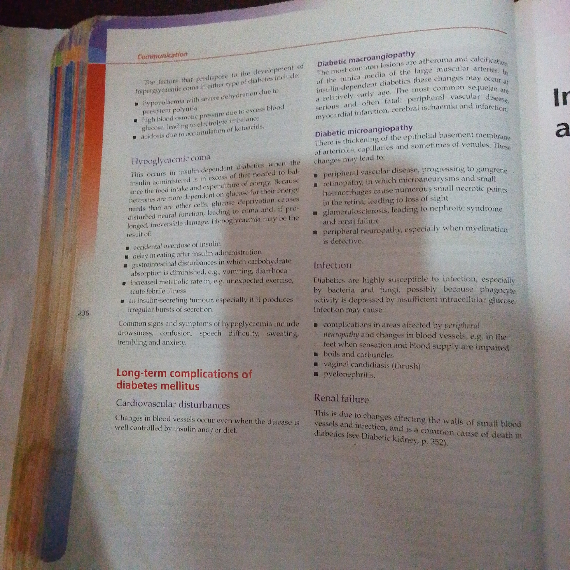 The image is a close-up of an open book, displaying text in English. The page features two columns of printed content related to diabetes and its complications. On the left side, there are headings like "Communication," "Hypoglycaemic coma," and "Long-term complications of diabetes mellitus." The right column contains sections on "Diabetic macroangiopathy," "Diabetic microangiopathy," "Infection," and "Renal failure." The text discusses symptoms, causes, and consequences of diabetes. A page number, "236," is visible on the left side. The lighting suggests the photograph was taken indoors, possibly with a flash, as there are some reflections and shadows on the page. There is no indication of Jalingo, Nigeria, or any other specific location within the image content.