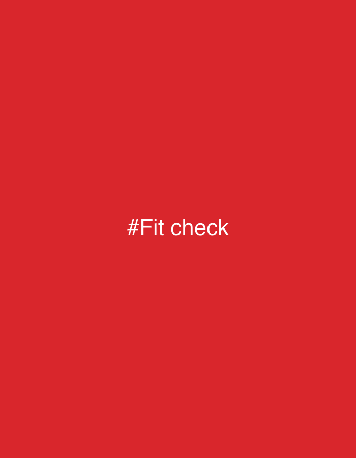 The image displays a solid, vibrant red background, completely filling the frame. Centered within this monochromatic field is the white text "#Fit check". The text is rendered in a clear, sans-serif typeface, providing a stark and easily legible contrast against the deep red. There are no other visible subjects, objects, people, or discernible scene elements. The image functions as a minimalist graphic, likely intended as a social media post or meme, signaling participation in the "fit check" trend, where individuals share their outfits. There are no notable details regarding time of day, weather, or specific location cues beyond the digital context suggested by the hashtag. The overall mood is neutral and direct, focusing entirely on the textual message.