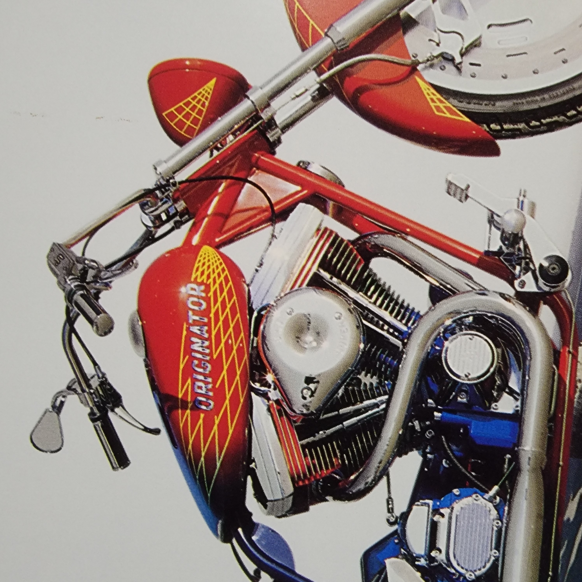 A custom red motorcycle is shown in a studio setting against a plain white background. The motorcycle features a prominent red fuel tank with blue accents and a yellow geometric pattern. The word "ORIGINATOR" is emblazoned on the fuel tank in a chrome-like font. The motorcycle has a large V-twin engine with chrome accents and ribbed black cylinders. A chrome exhaust pipe curves along the side. The handlebars are chrome with black grips and mirrors. The front fender is red and also features the yellow geometric pattern. The front wheel has a chrome rim and spokes. The overall impression is of a highly customized and visually striking motorcycle.