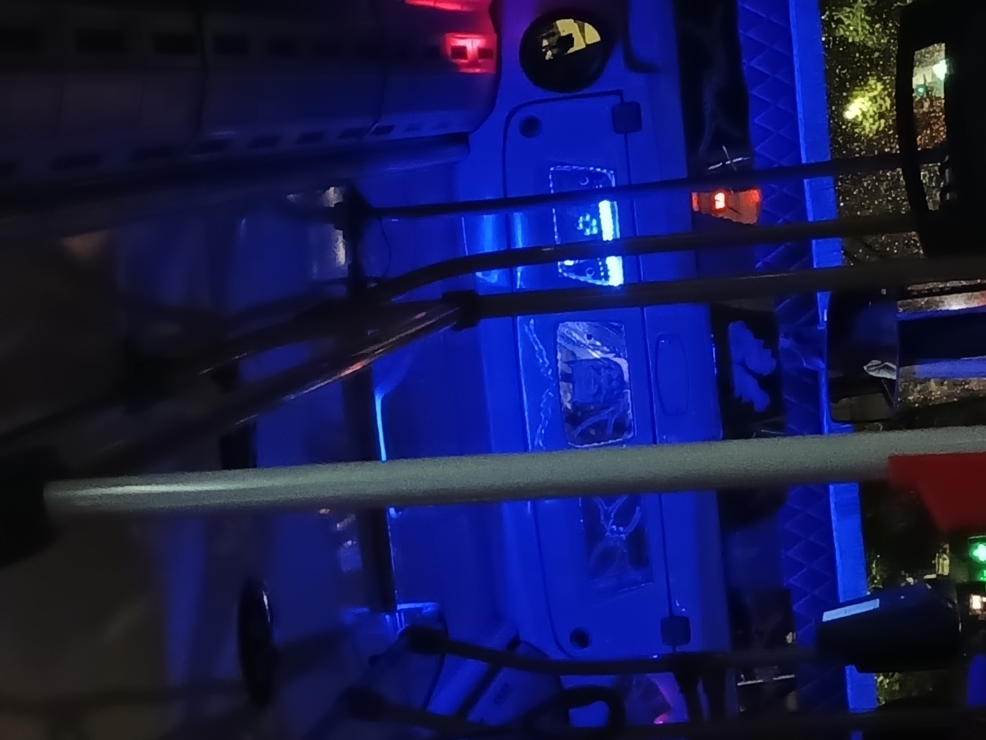 The image shows a blue and white object under blue lighting. The location could possibly be Buenos Aires, Argentina, as lights outside indicate nighttime in a city. However, without further details it is difficult to precisely pinpoint the location. There are red and green lights visible outside. The object appears to have a circular hole and some rectangular recessed areas. There are also some bars or railings visible.