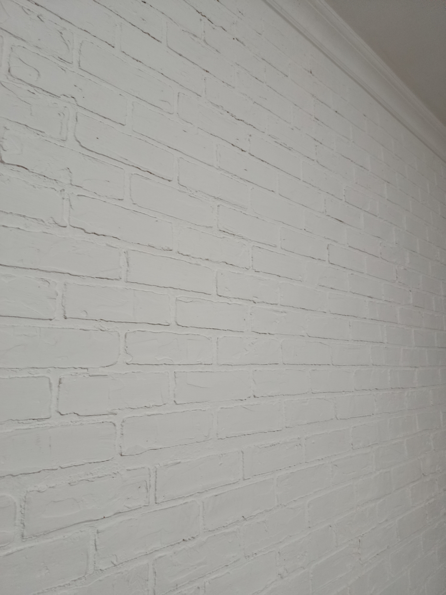 The image shows a white brick wall that recedes into the distance. A white molding runs along the top edge of the wall. The lighting is even, and there are no people or objects visible in the scene. The context of Grozny, Russia is not evident from the image itself.