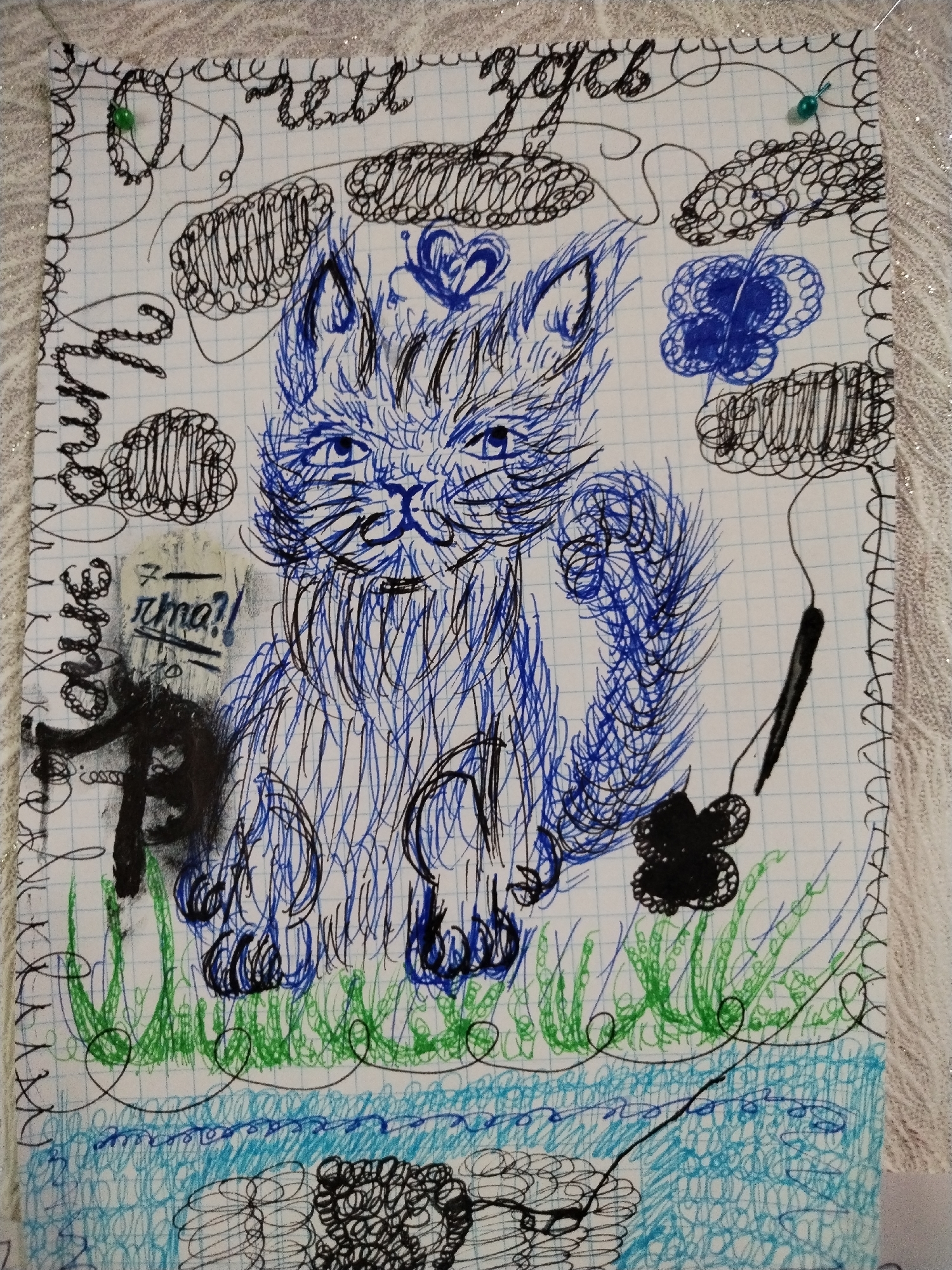 A sketch on graph paper depicts a blue and black drawing of a cat sitting in grass with a blue body of water below. The cat has large, expressive blue eyes and a tuft of fur on its head with a blue heart drawn above it. The cat's tail is bushy and extends to the right. To the left of the cat, there is some graffiti-like scribbling in black and some Russian text. The background of the sketch is filled with random scribbled shapes and patterns in black and blue. The paper is bordered by a decorative pattern. Two green pushpins are visible, one near the top left and another near the top right corner of the paper. The image is not set in a specific location in the city of Pokrovka, Russia, nor does it depict any identifiable environmental features of that city.