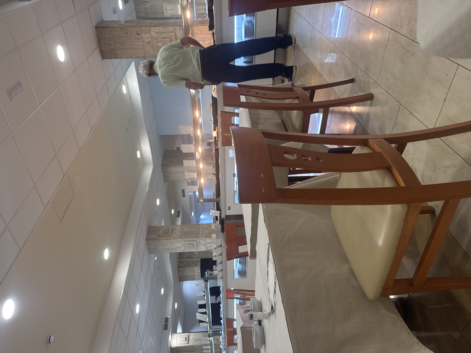 The image shows a man, appearing to be a tourist, in a buffet-style restaurant. He is standing in front of a food serving station, looking at the food options. The restaurant is furnished with tables and chairs, and the lighting suggests it is daytime. The floor is tiled. The man is wearing a light green short-sleeved shirt and dark pants. The overall scene suggests a typical dining experience in a restaurant. Fuengirola, Spain is a popular tourist destination known for its beaches and restaurants, and this scene is consistent with what one might find in such a location.