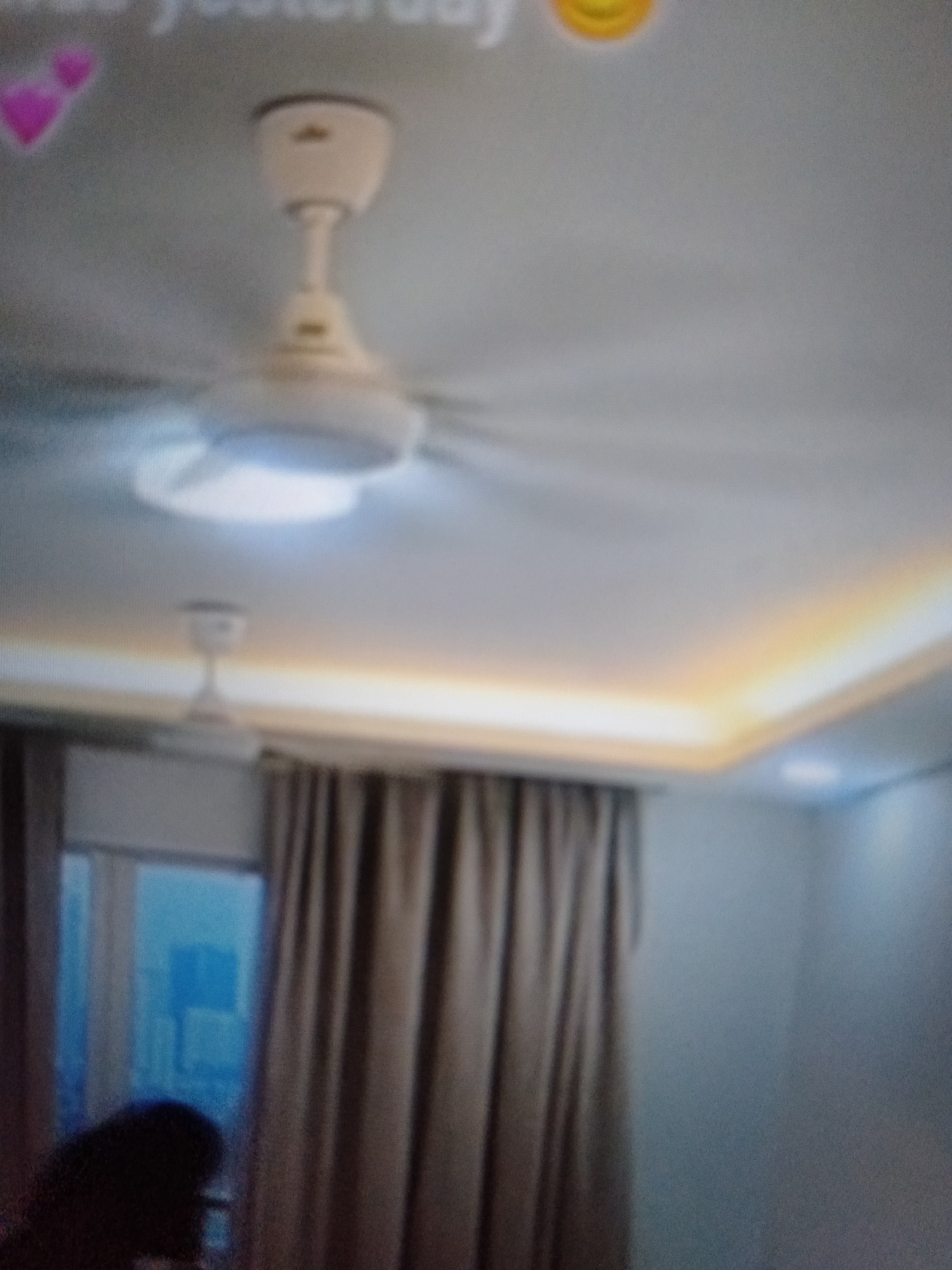 The image shows a dimly lit room with a ceiling fan. There are also some curtains and a window visible. The overall impression is that of a residential interior. It is not possible to determine the location in Jalingo, Nigeria from the image.